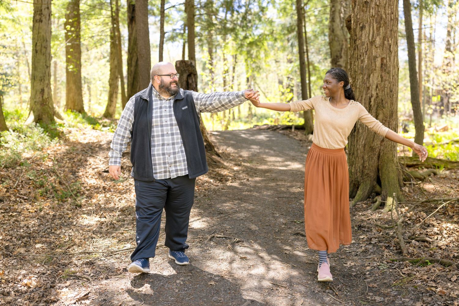 Playful couple walking and laughing together on a wooded forest path. Ottawa Wedding Photographer