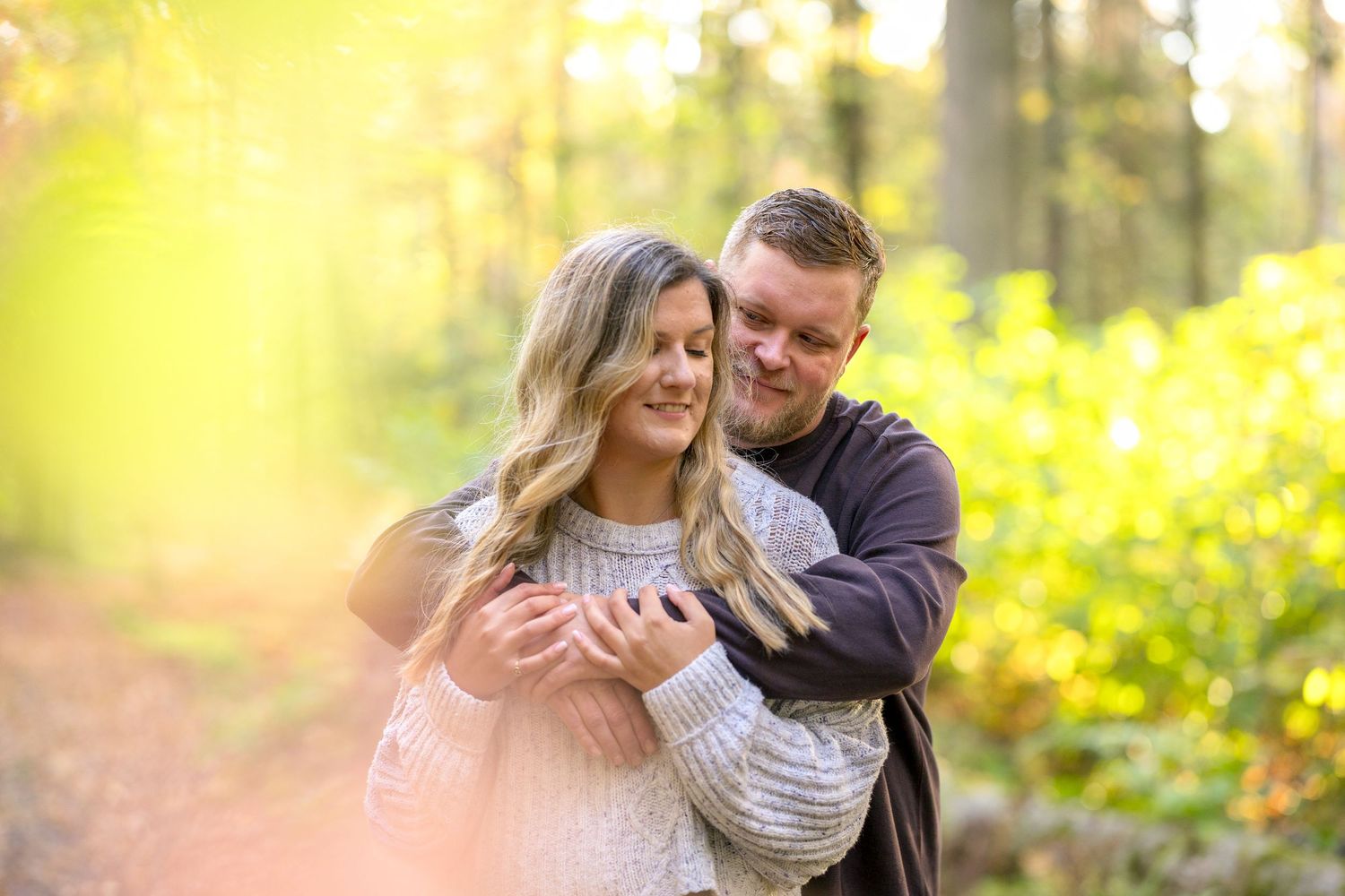 Couple sharing joyful moment in sunlit wooded area. Ottawa Portrait Photographer