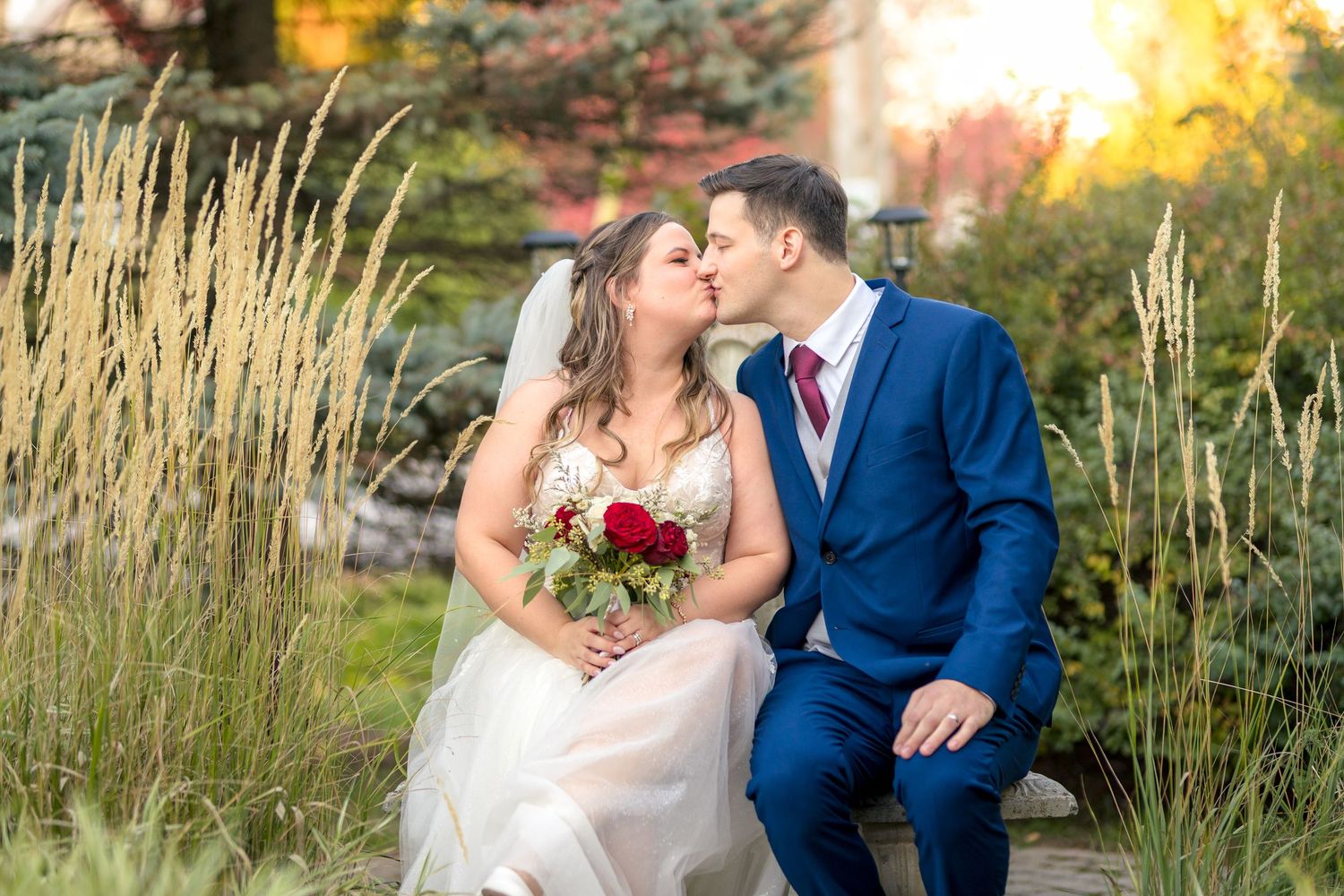 A couple in wedding attire shares romantic moments in a garden setting with tall grass at golden hour. Ottawa Photographer Tim Gowling