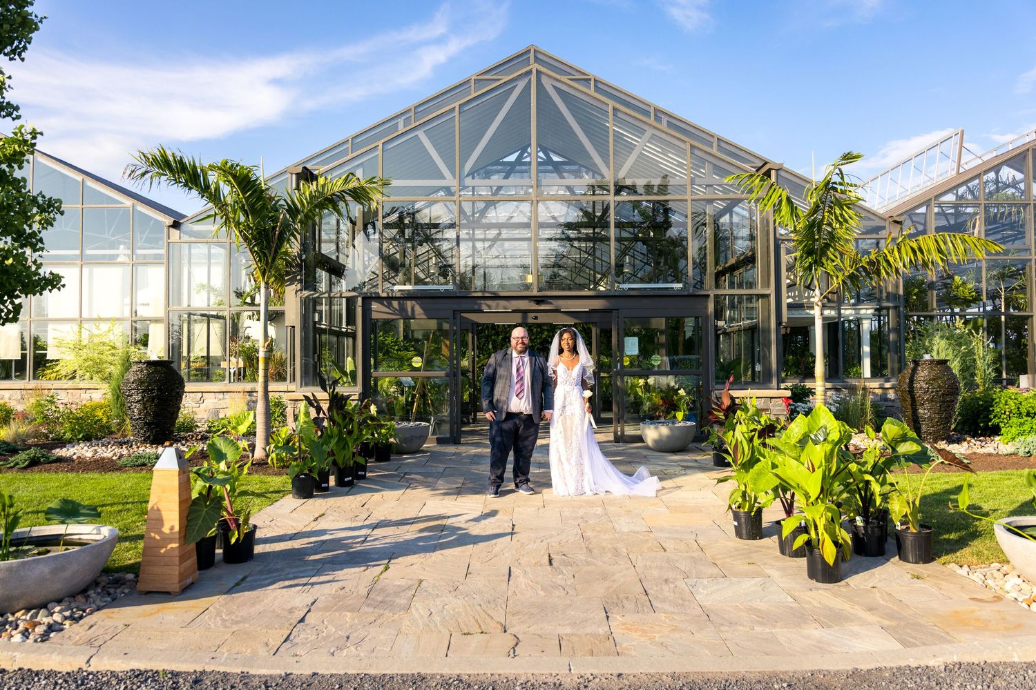 A modern glass greenhouse with ornate tropical landscaping and stone pathway leading to the entrance. Tim Gowling Photography