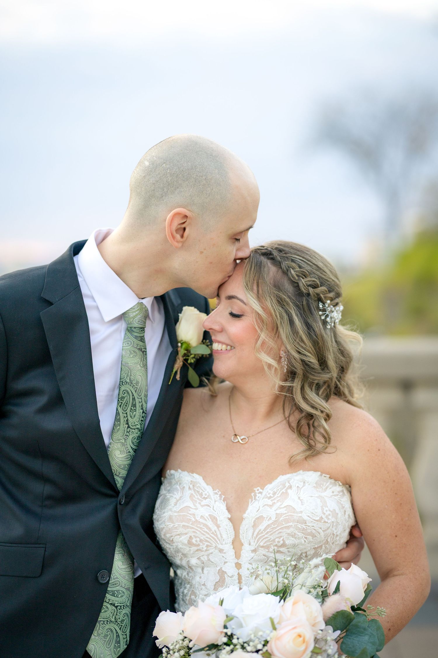A wedding couple poses together on a stone terrace at the Fairmont Château Laurier with fall trees. Ottawa Wedding Photographer