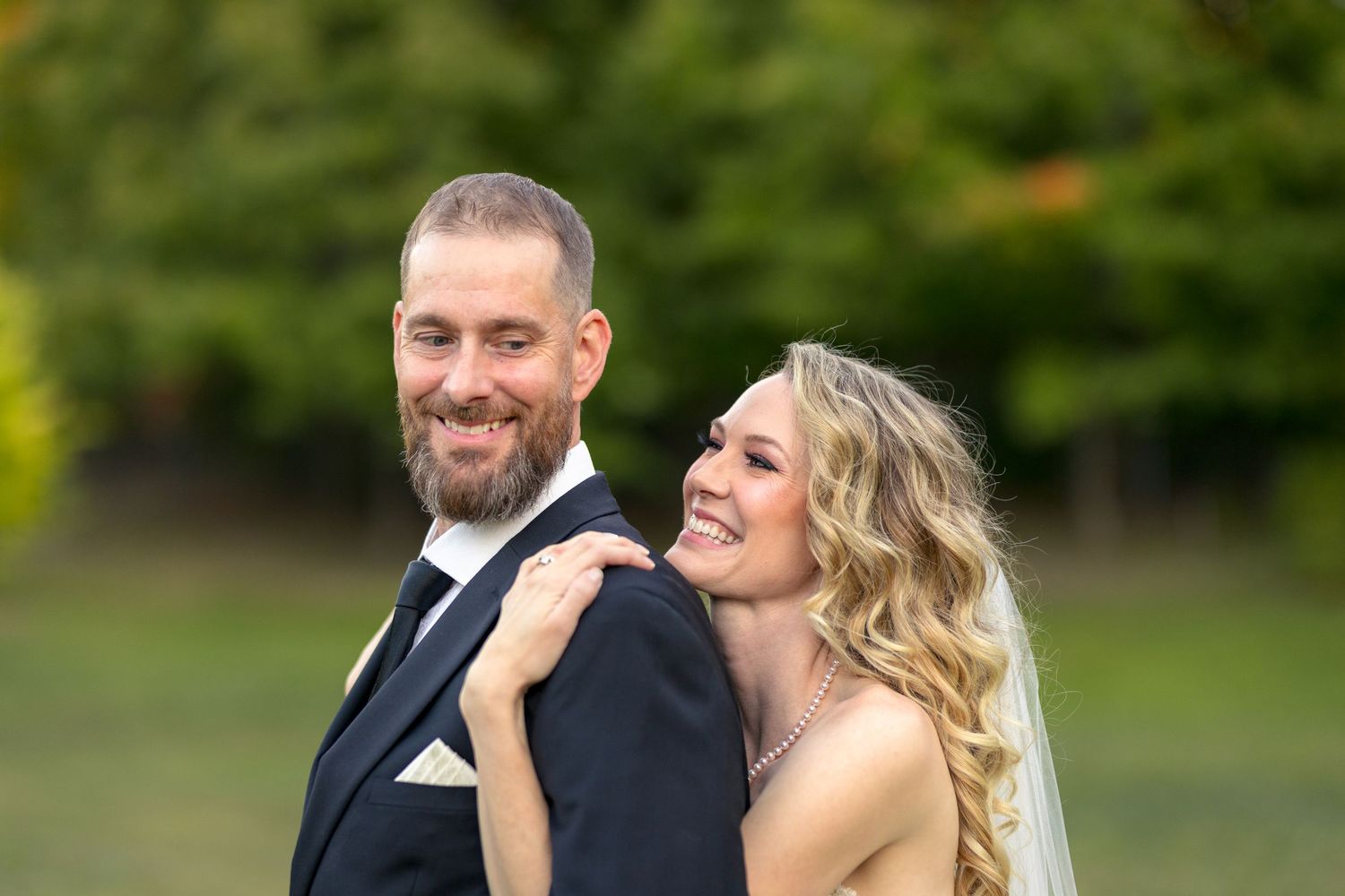 A happy wedding couple shares a joyful moment together outdoors in a garden setting. Ottawa Wedding Photographer