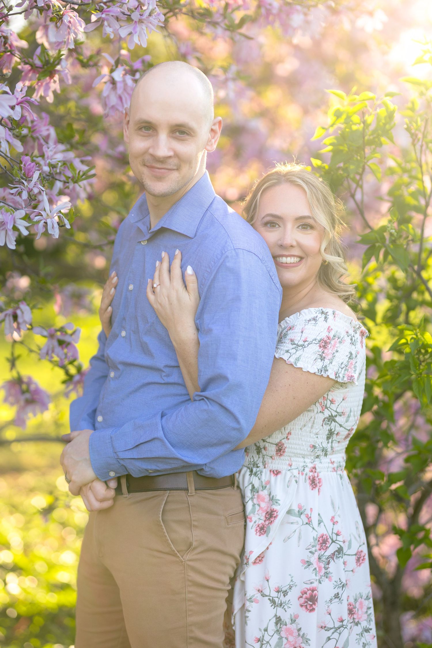 A romantic spring portrait of a couple embracing under blooming purple flowers in golden sunlight. Ottawa Wedding Photographer