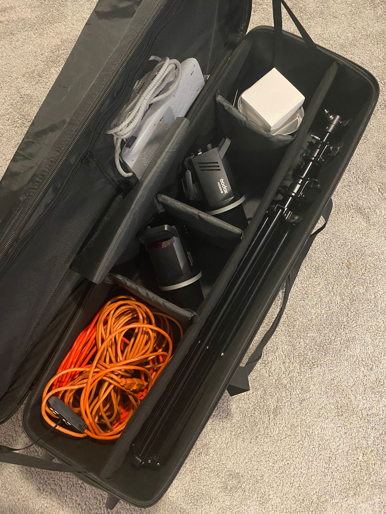 A black equipment case showing orange cables, power supplies, and white electronic components neatly organized in compartments.