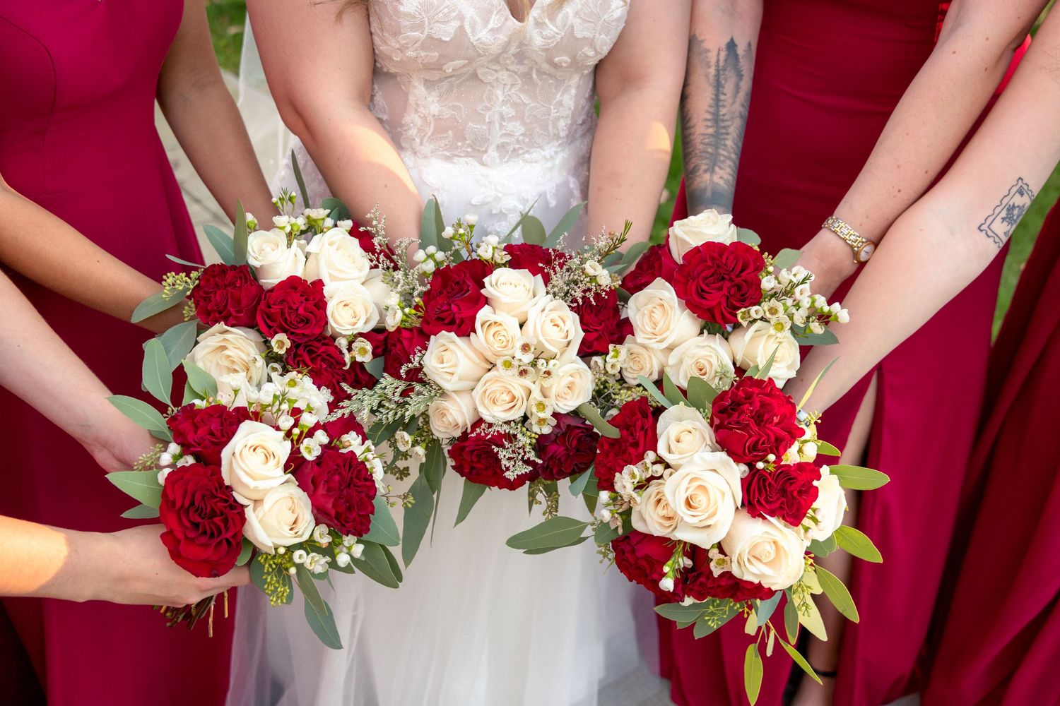 Wedding bouquets featuring deep red roses and white flowers arranged in a classic style against a burgundy background. Ottawa Photographer