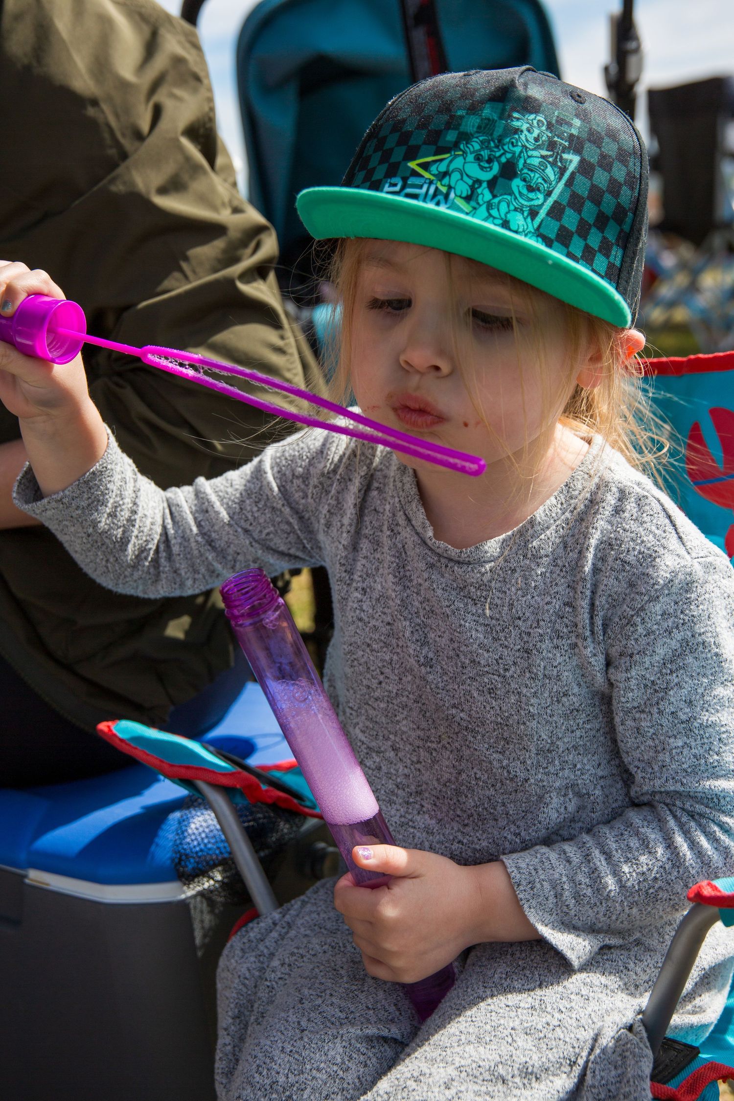 Child in a green baseball cap playing with colorful toys.