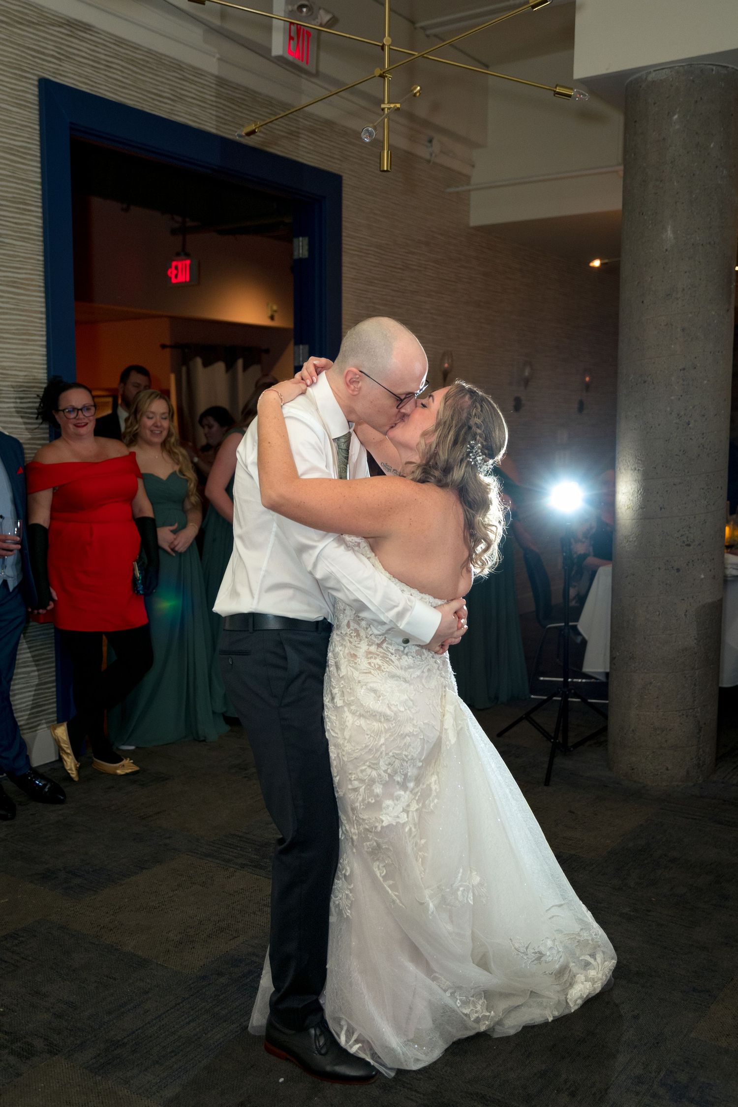 A couple shares their first dance at a wedding reception in a dimly lit venue with guests watching. Ottawa wedding photographer