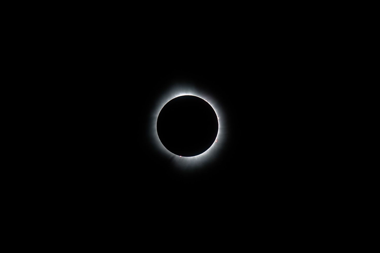 A total solar eclipse shows a bright corona ring against a black sky.