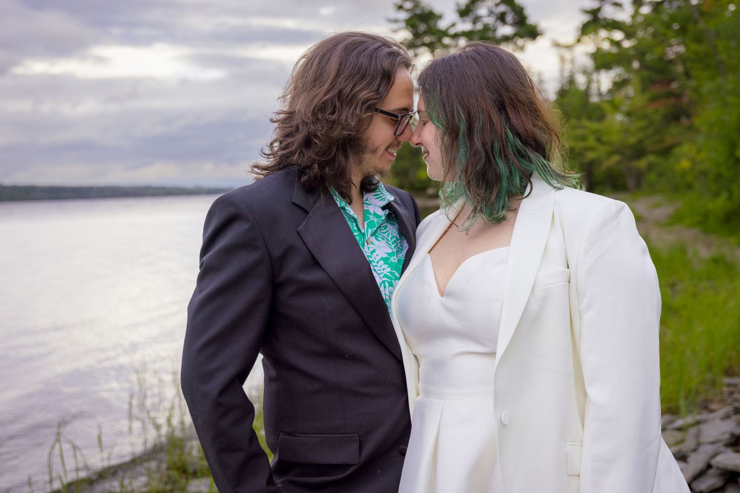 A couple in wedding attire shares an intimate moment by a lakeside. Ottawa Wedding Photographer