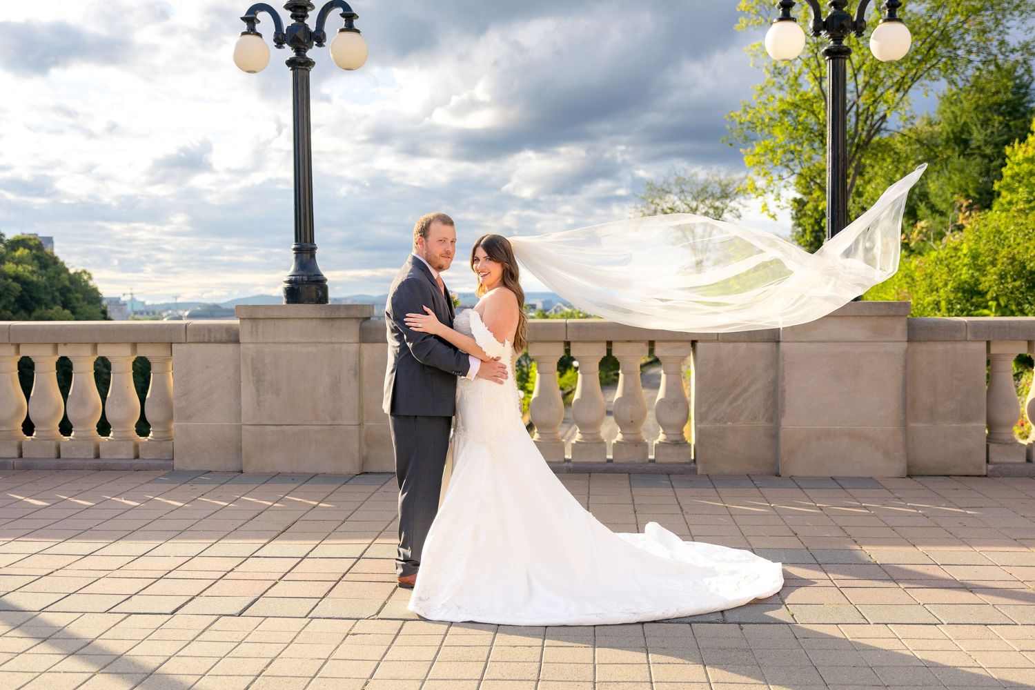 Newlyweds share a romantic moment on an elegant stone terrace overlooking a scenic landscape at sunset. Ottawa Photographer Tim Gowling