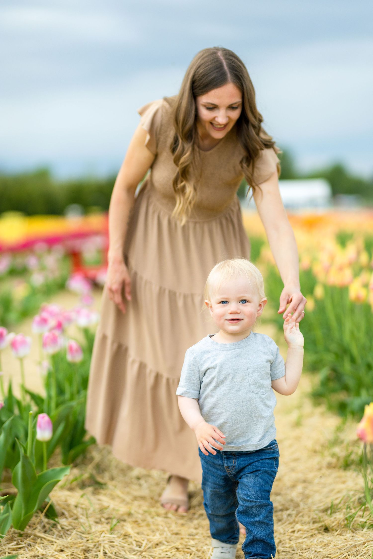 A parent and toddler explore a colorful tulip field on a sunny spring day. Ottawa Wedding Photographer