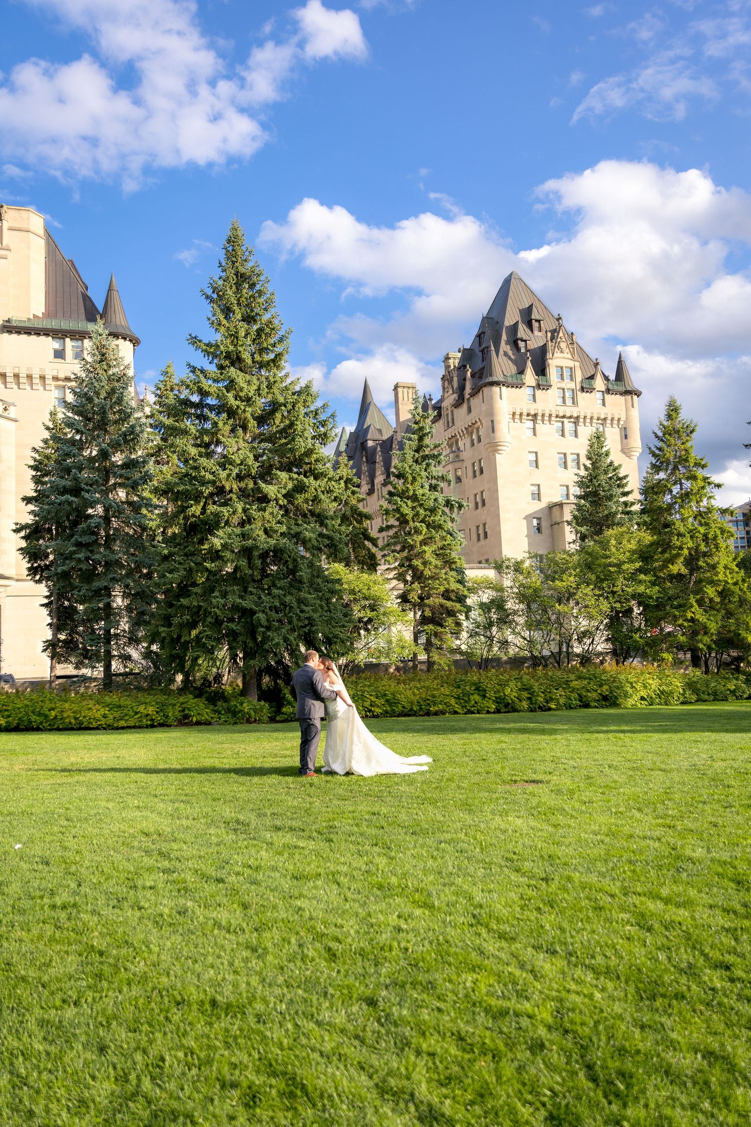 The Bride & Groom embrace with the grand Chateau Laurier behind them for their formal wedding day formal photographs in Ottawa