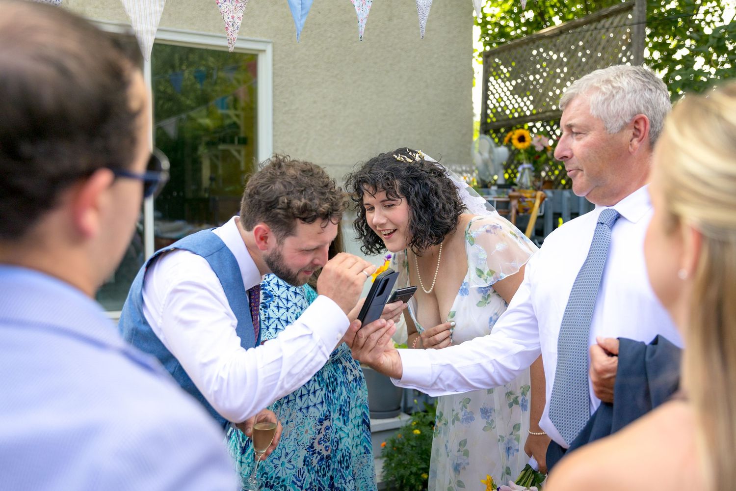 Wedding reception guests celebrating outdoors under white bunting decorations.
