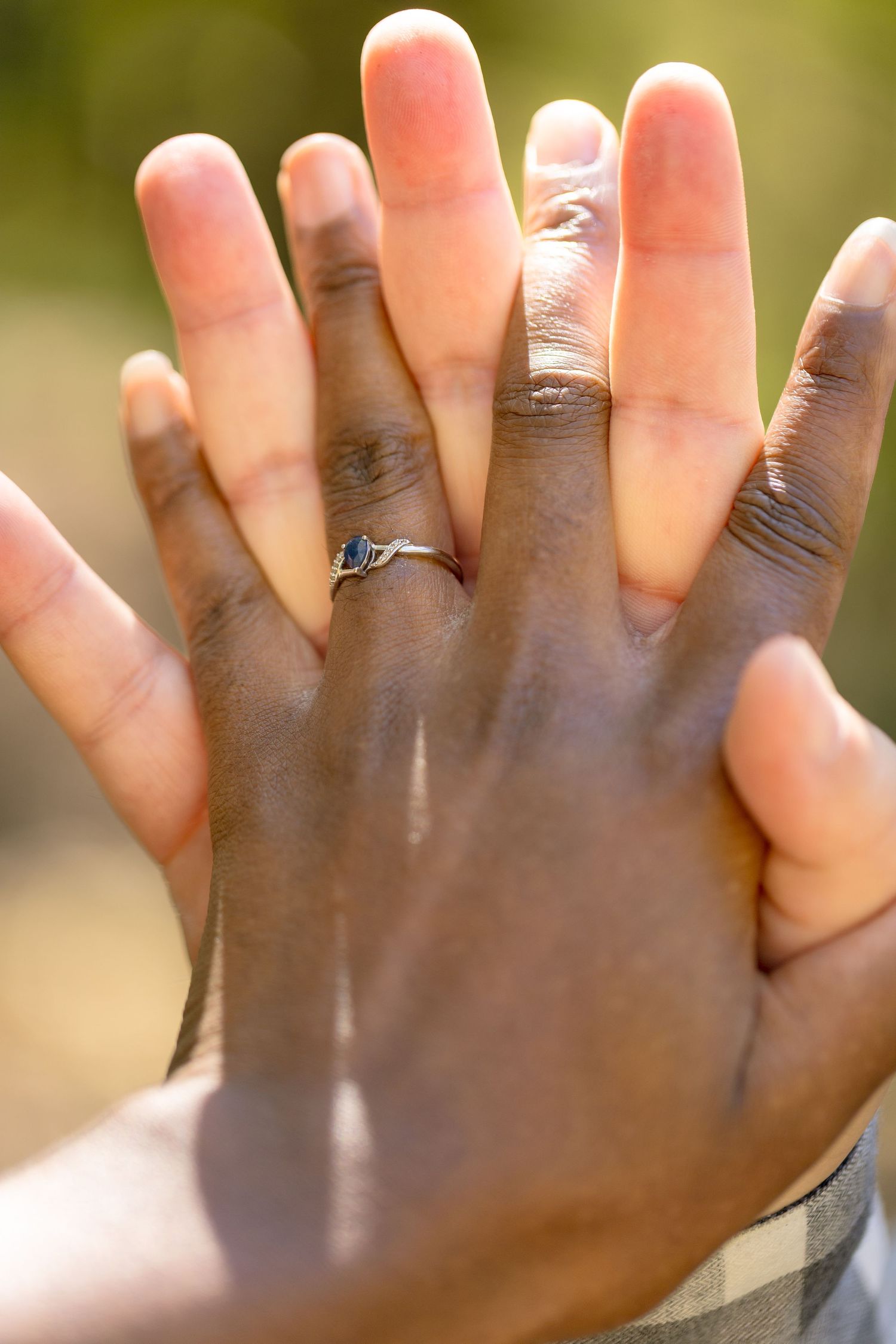 Close-up of hands with engagement ring against sunlit natural background. Ottawa Wedding Photographer