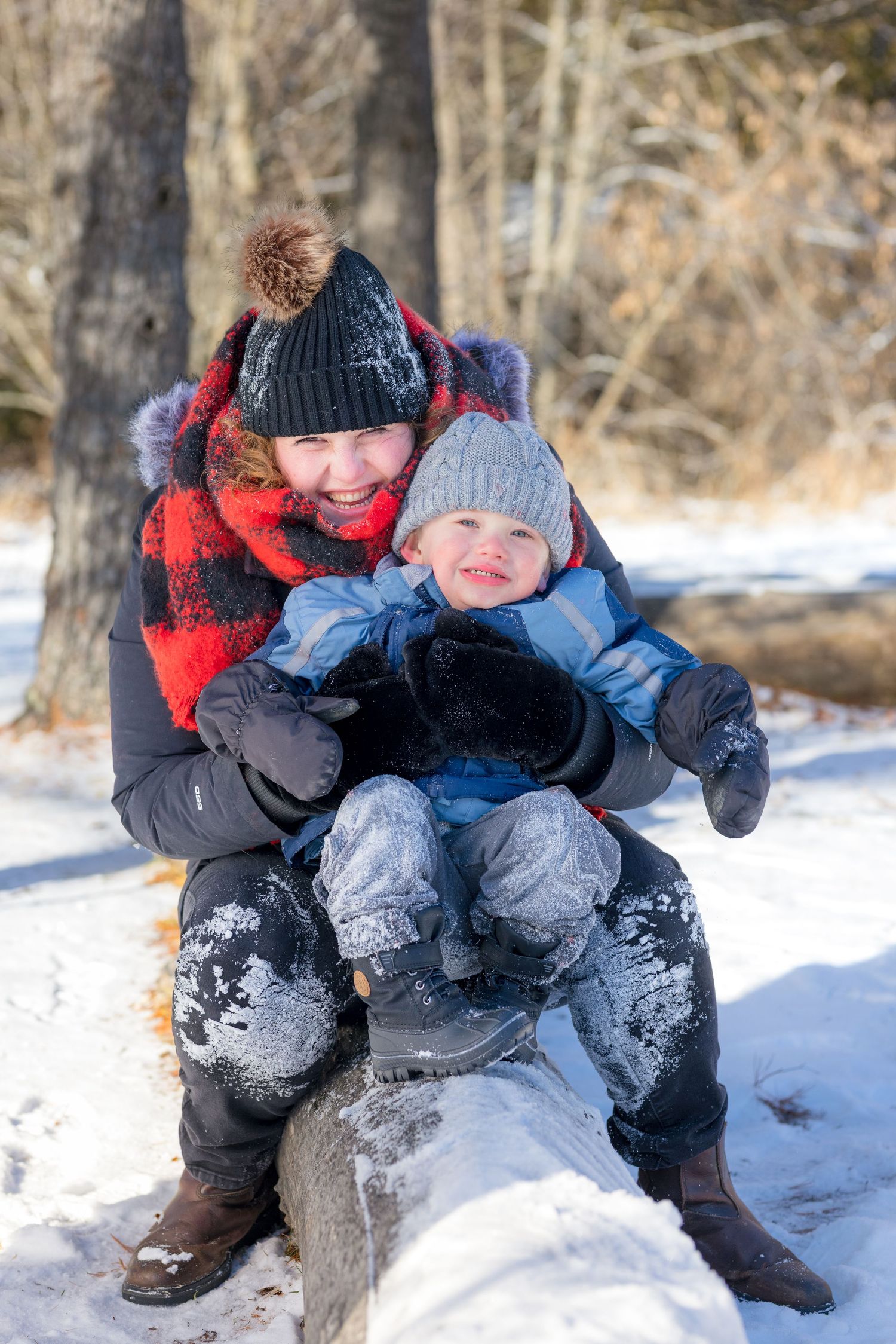 A child plays in deep snow wearing winter gear and boots. Ottawa Family Photographer