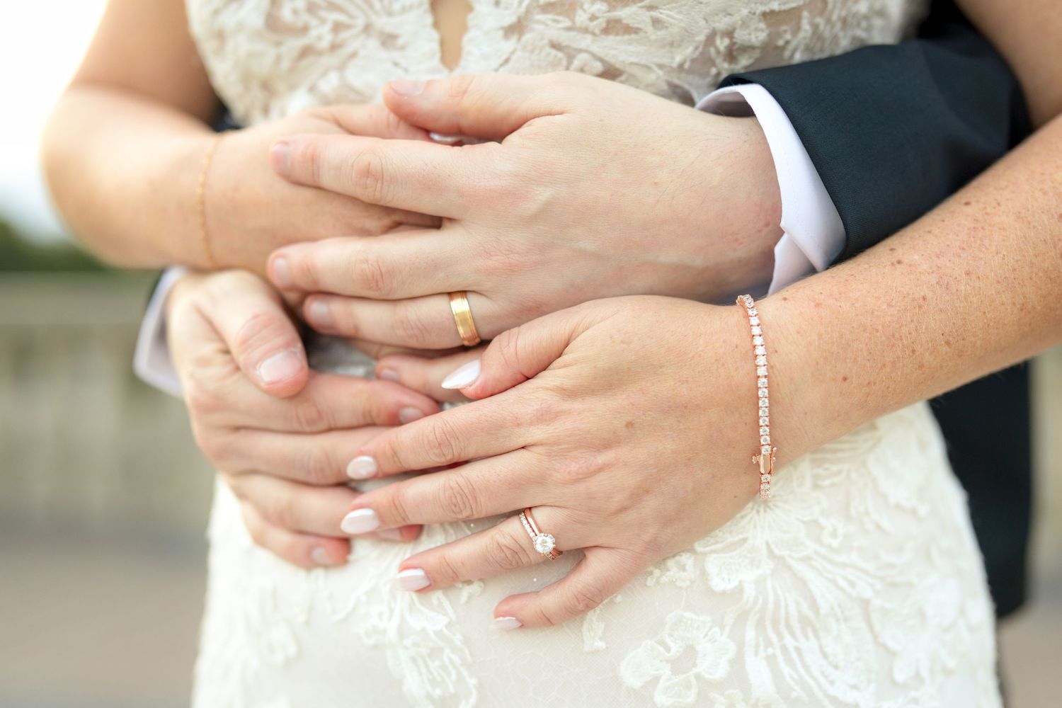 A close-up view of hands resting on a white wedding dress showing delicate details. Ottawa Wedding Photographer