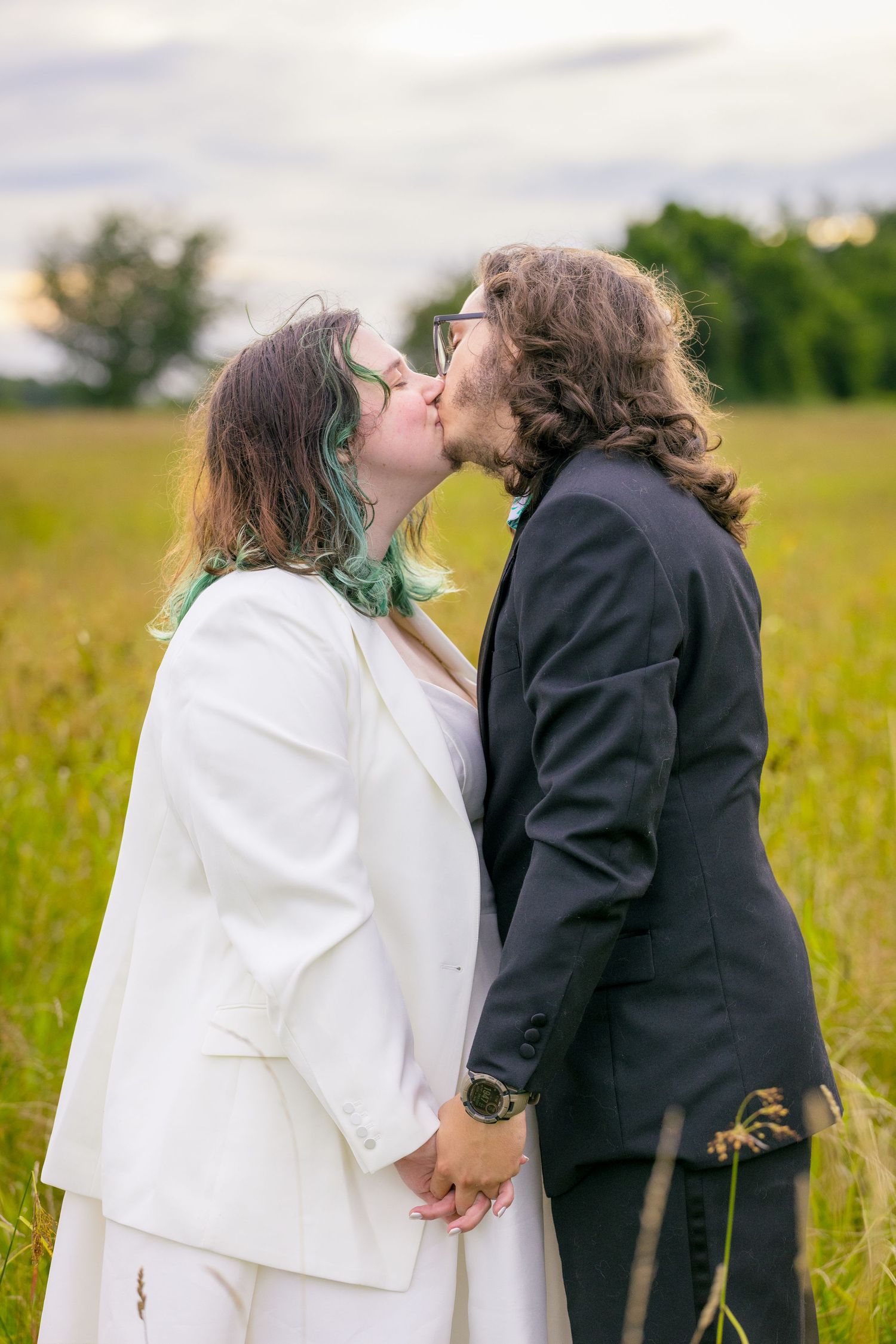 A couple shares a romantic kiss in a sunlit meadow wearing wedding attire. Ottawa Wedding Photographer