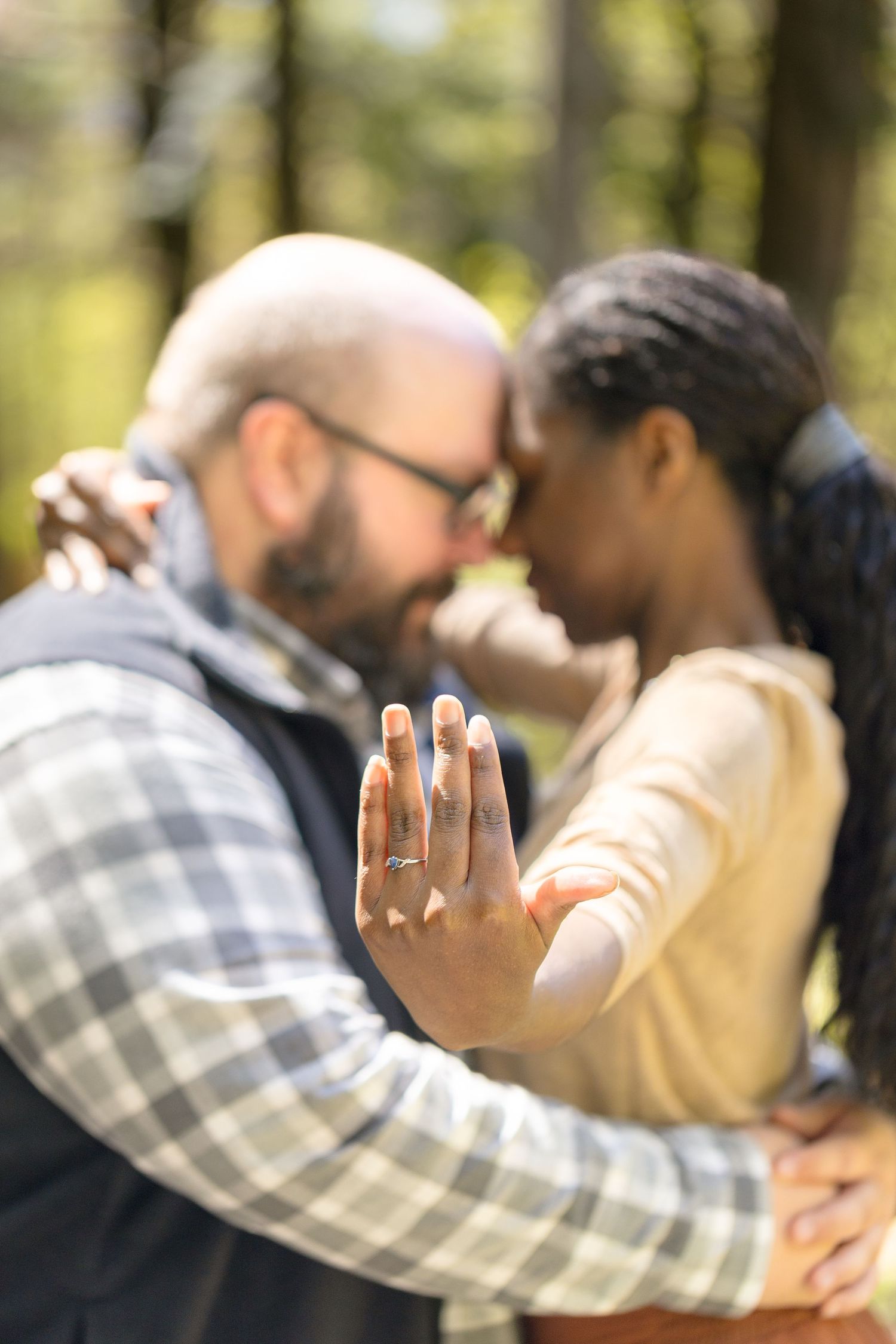 A couple sharing an intimate moment outdoors while showing off an engagement ring in the foreground. Ottawa Wedding Photographer