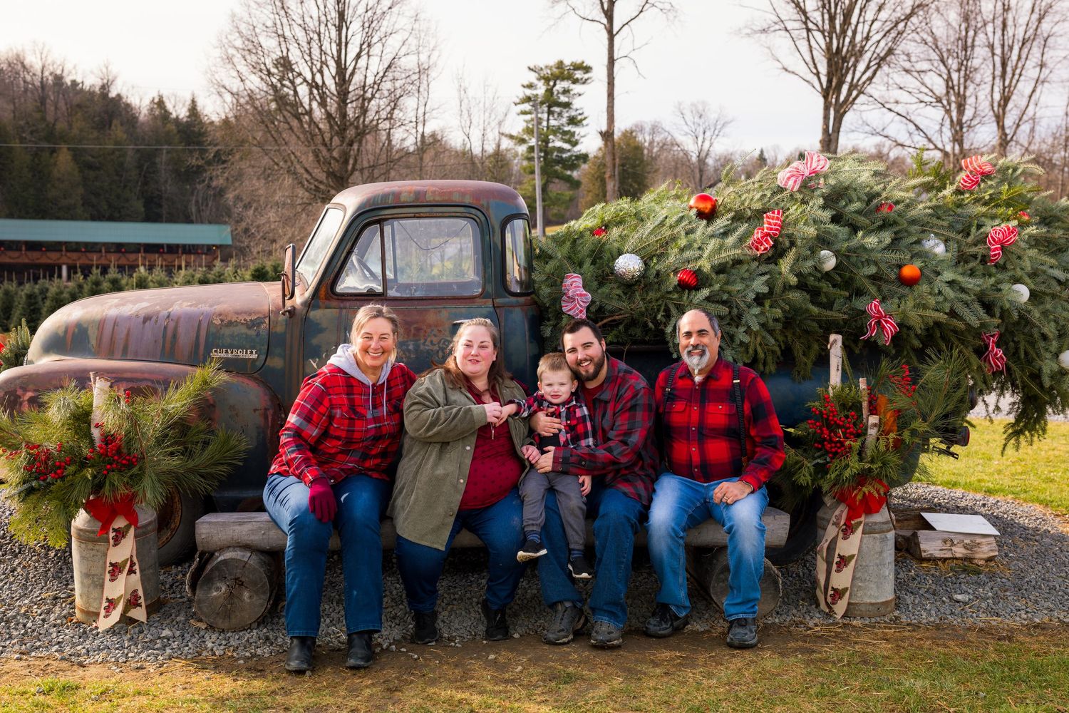 A vintage rustic truck decorated with a large Christmas tree, holiday decorations and buffalo plaid accents.