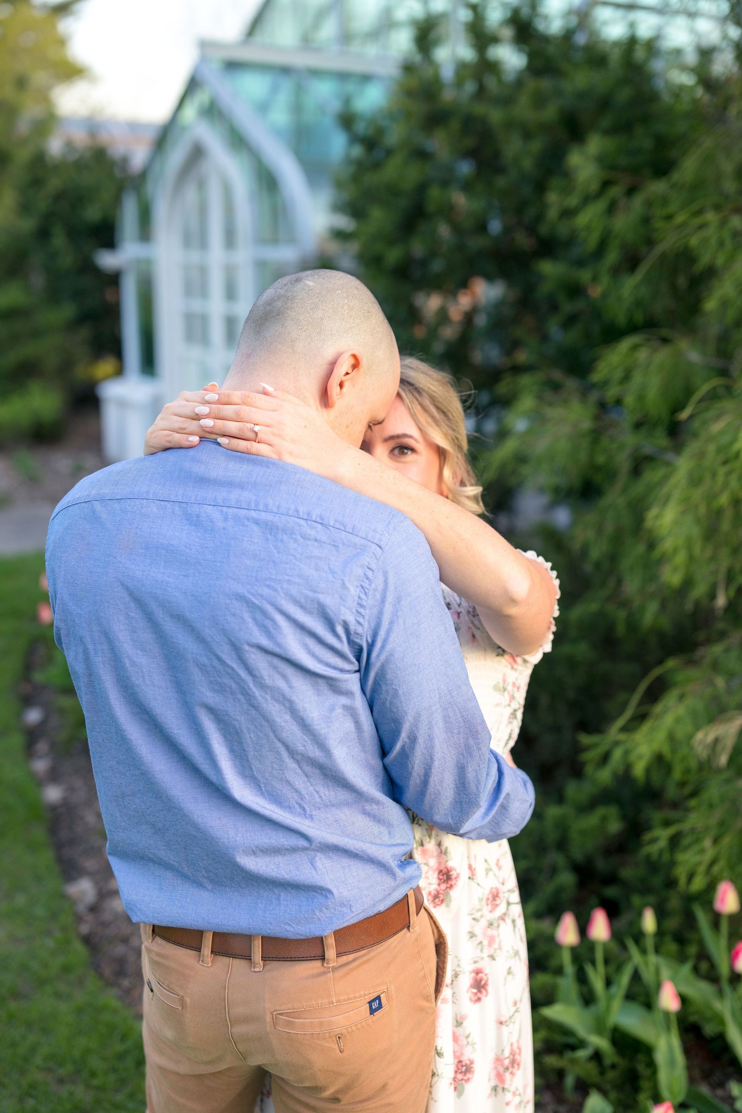 An intimate embrace captured near a garden greenhouse with lush greenery. Ottawa Wedding Photographer