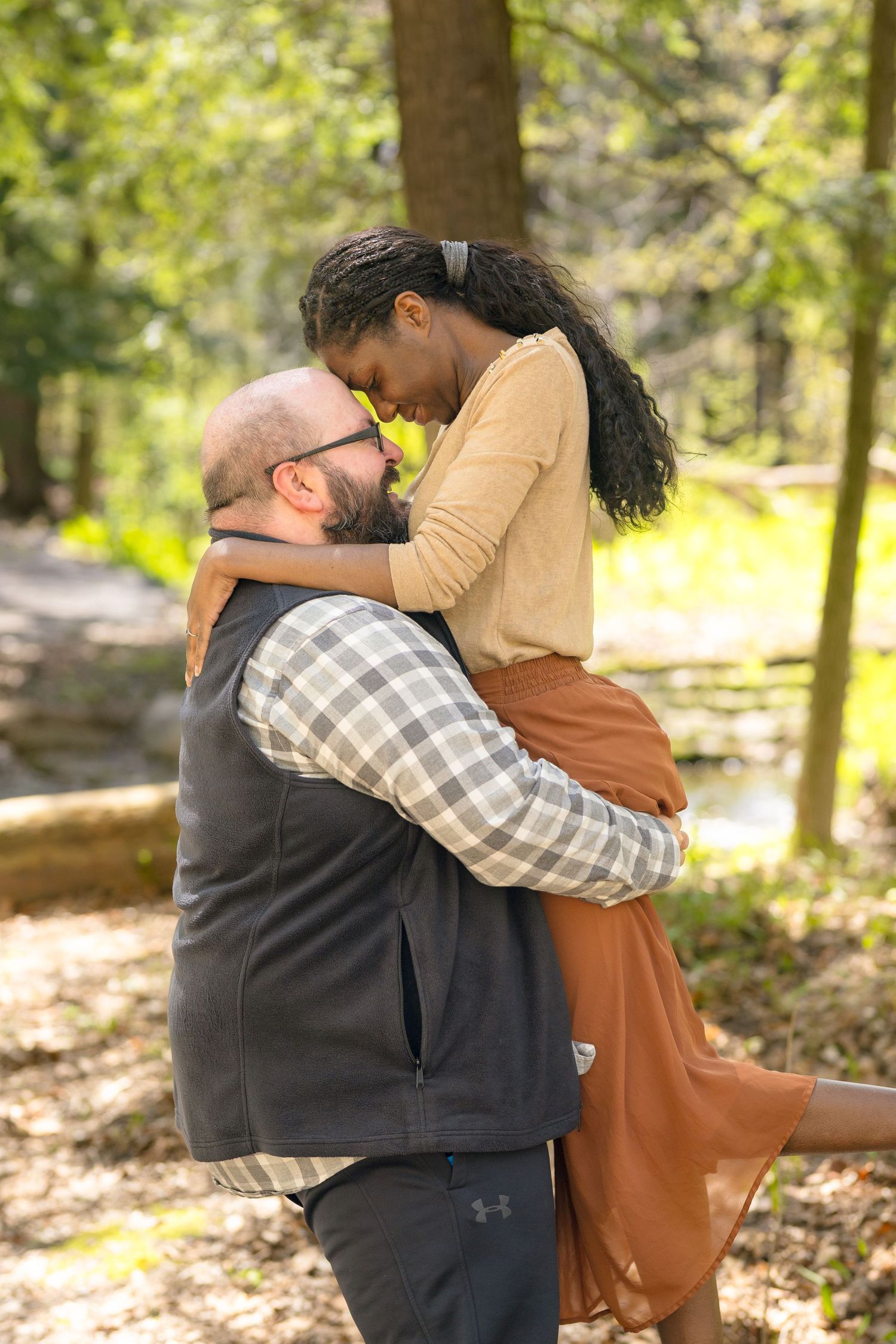 A romantic embrace between a couple in a sunlit forest setting. Ottawa Wedding Photographer