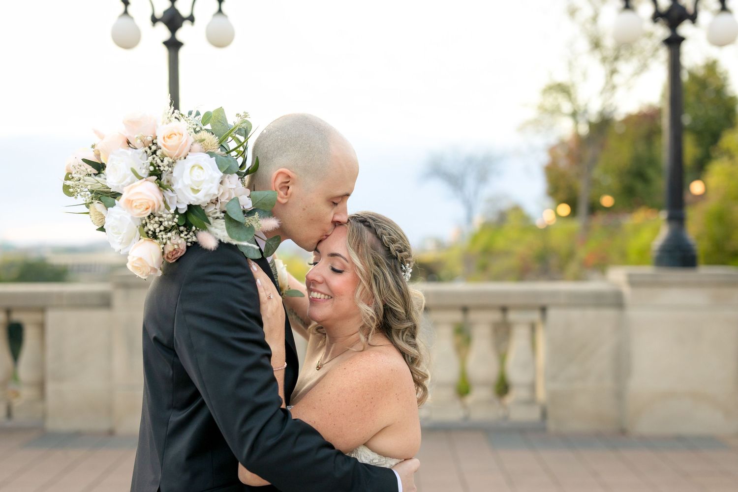 A romantic wedding couple embraces on the terrace of the Château Laurier with a floral bouquet at sunset. Ottawa Wedding Photographer