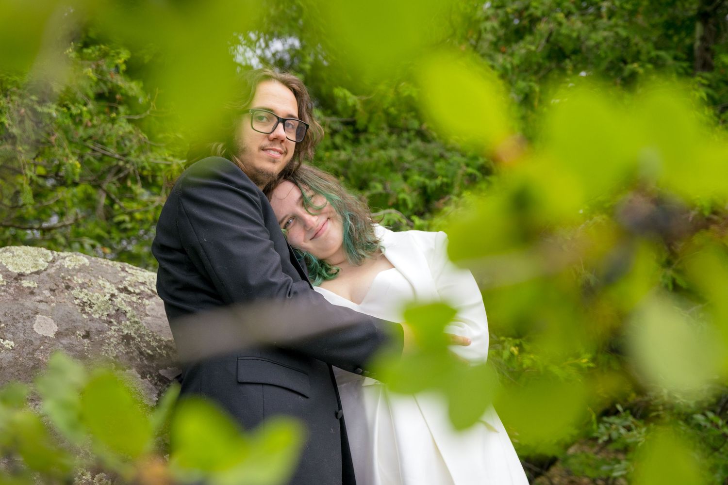 A tender moment between newlyweds captured through green foliage. Ottawa Wedding Photographer