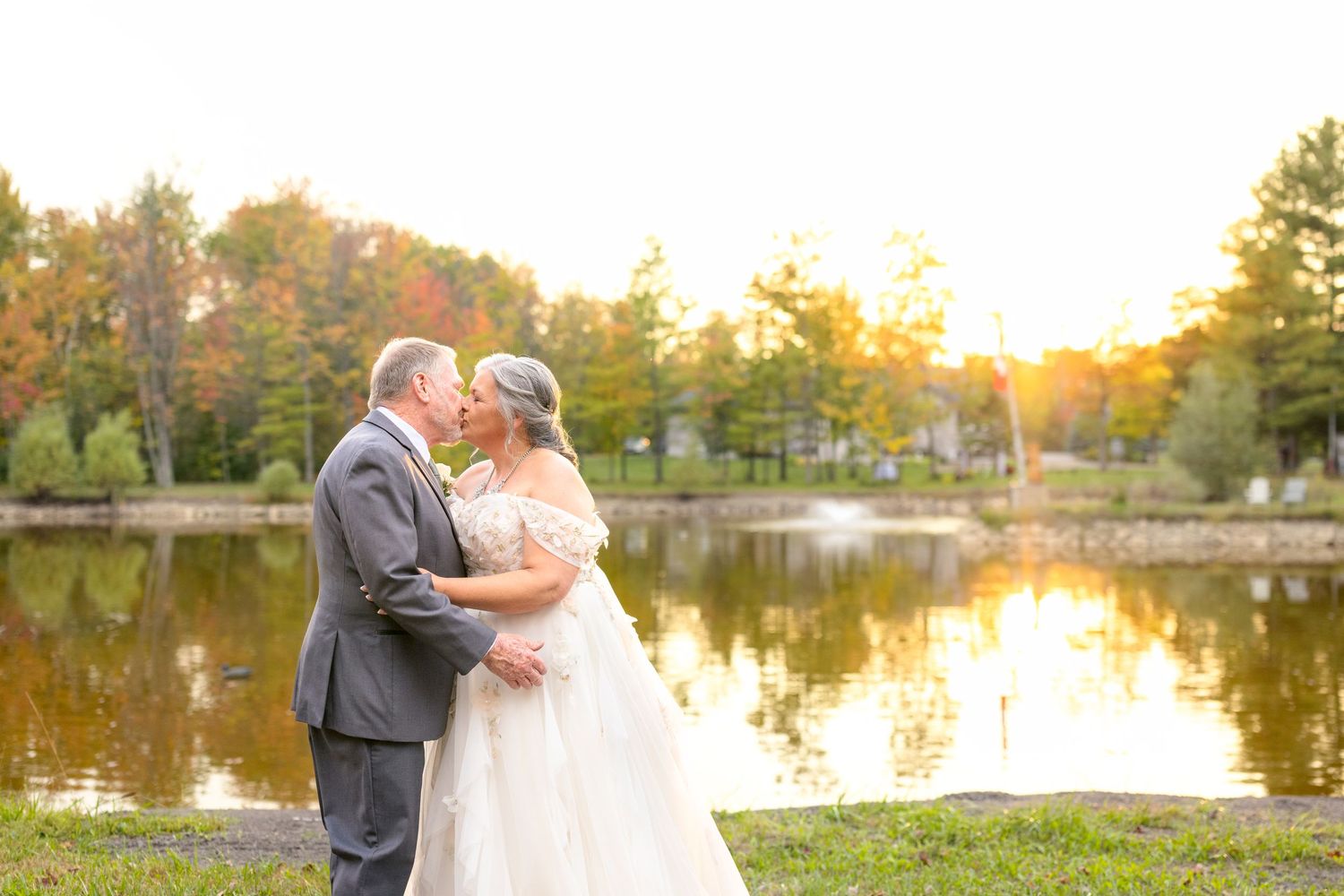 Romantic sunset wedding photos captured by a lake with autumn foliage creating a beautiful natural backdrop. Ottawa Wedding Photographer