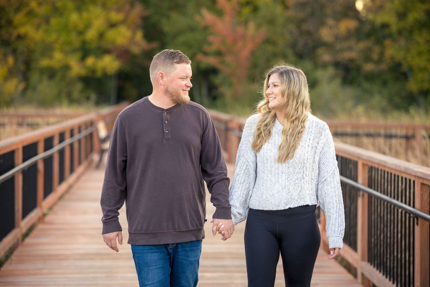 Couple walking hand in hand on wooden boardwalk during autumn. Ottawa Portrait Photographer