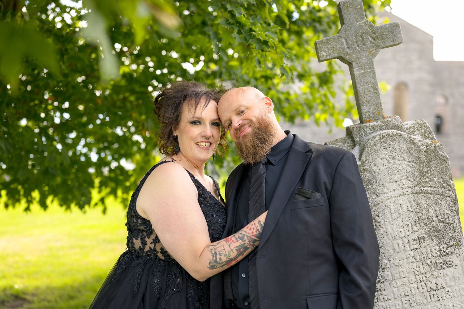 A couple shares a romantic moment next to a stone grave at St Raphael's Catholic Church Ruins with Ottawa Wedding Photographer