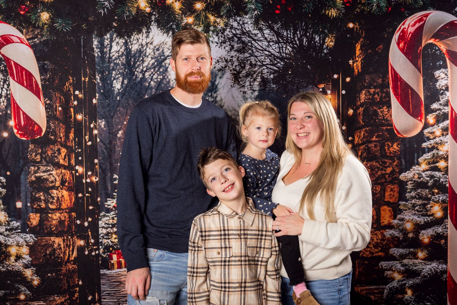Family holiday portrait with candy cane decorations and festive backdrop.