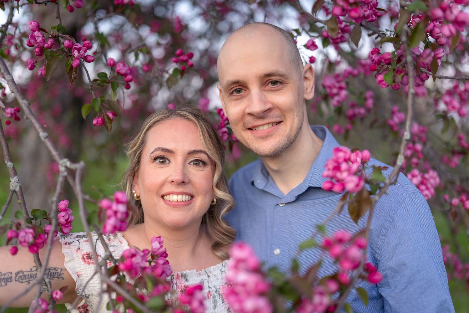Happy couple posing among vibrant pink cherry blossoms in full bloom. Ottawa Wedding Photographer