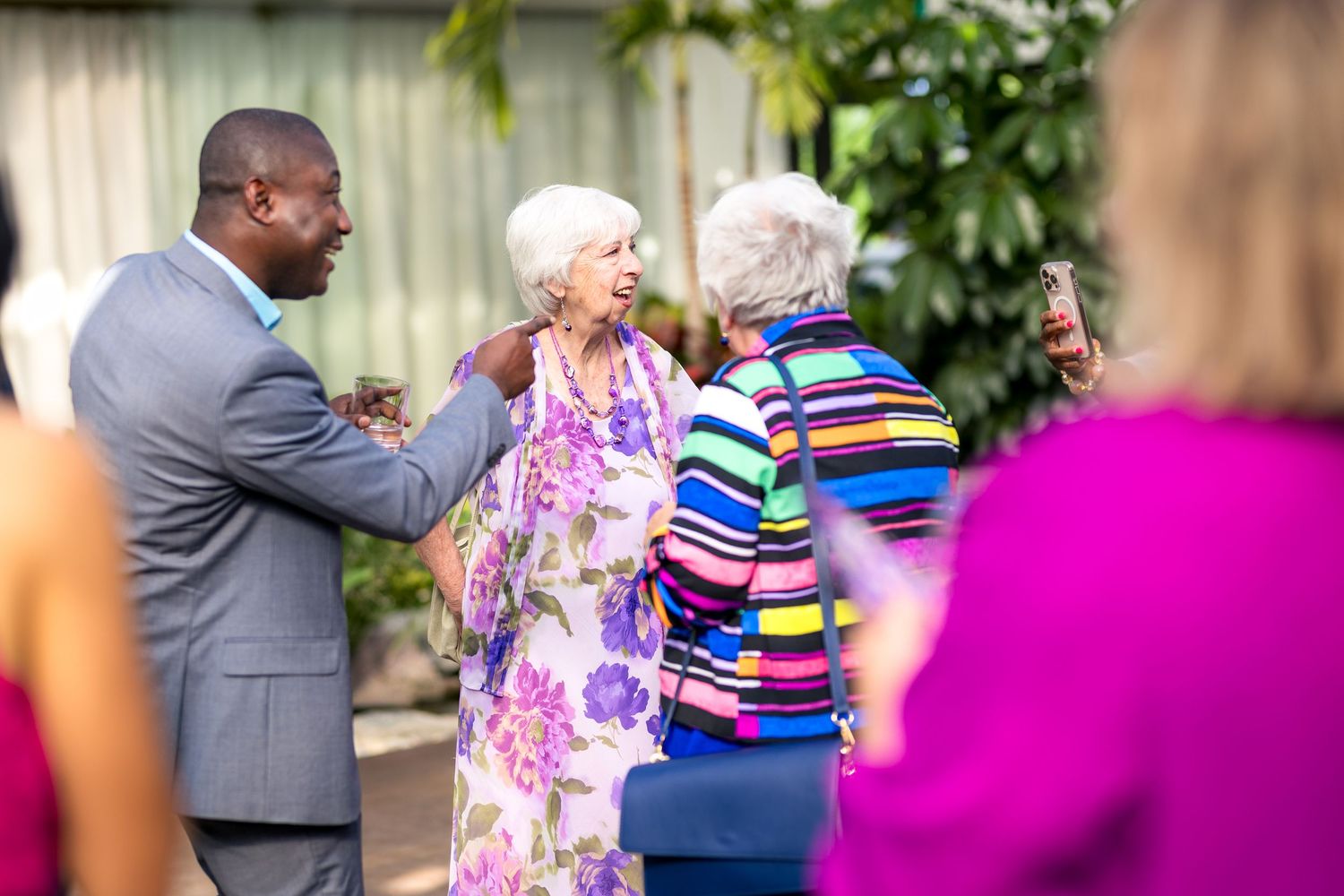 People celebrate at an outdoor party wearing colorful attire including florals and stripes.