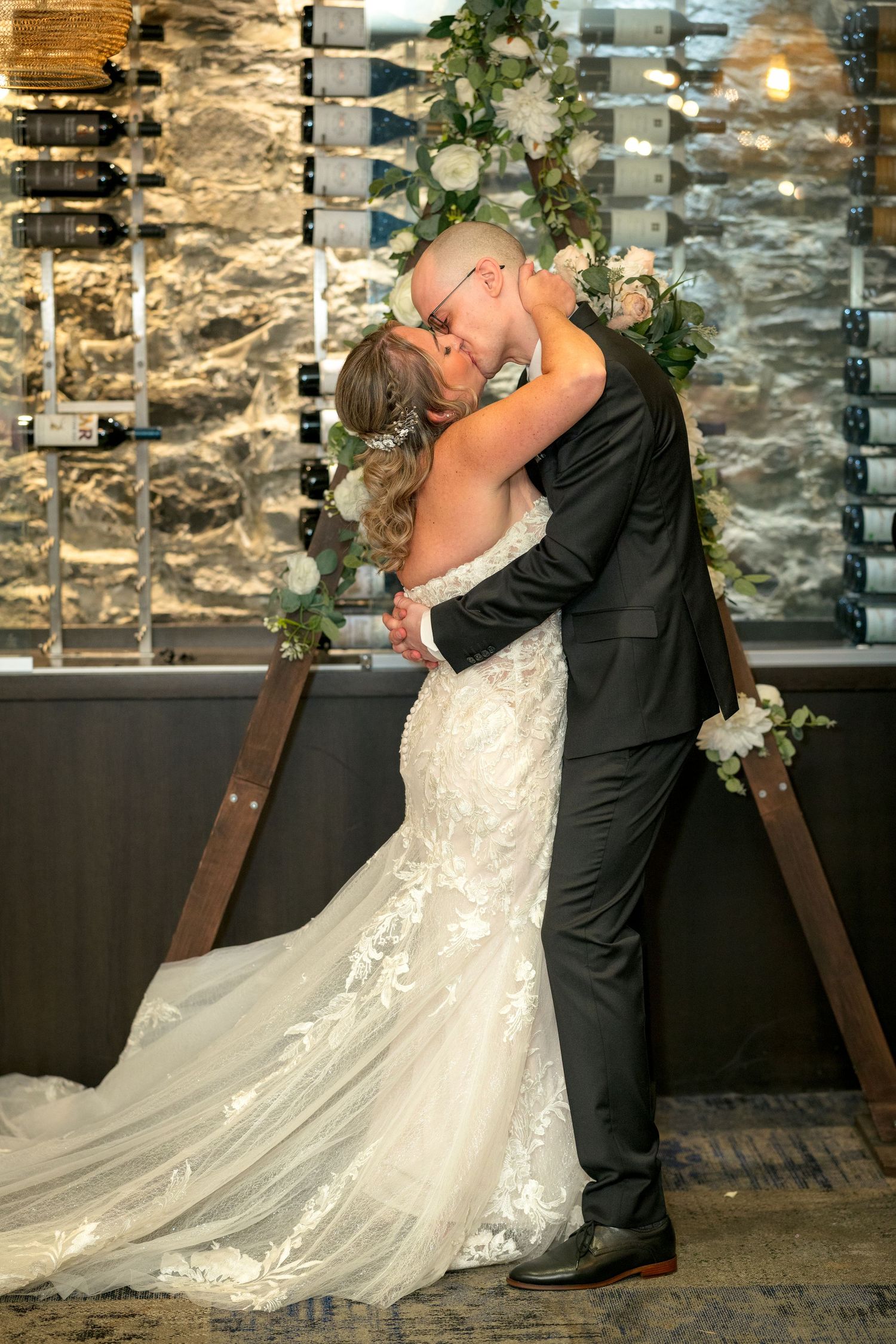 A romantic wedding couple shares a passionate first kiss against a rustic stone wall inside sidedoor restaurant Ottawa wedding photographer