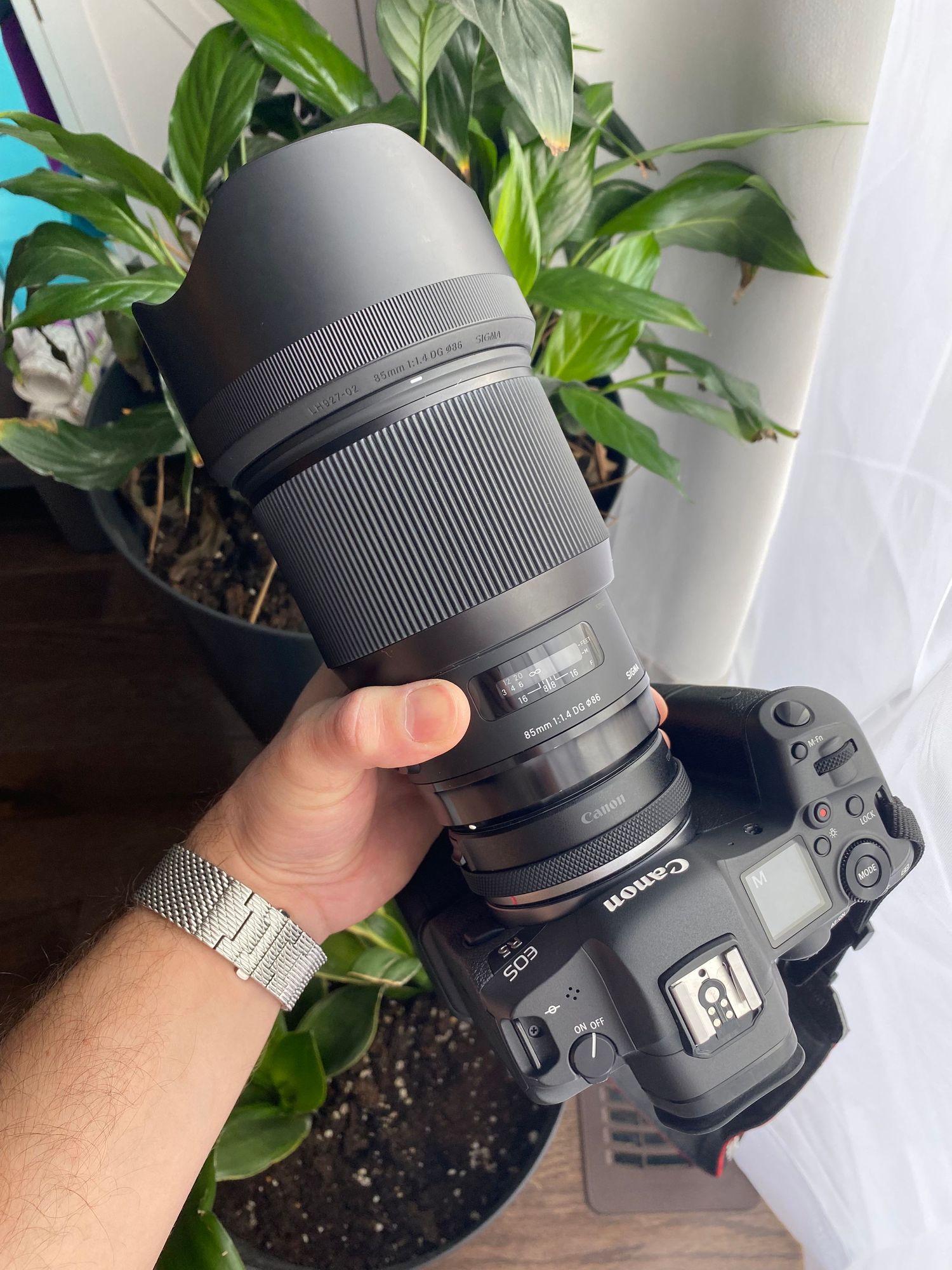 Sigma 85mm f/1.4 DG Art lens mounted on a Canon R5 mirrorless camera held by a photographer, perfect for wedding portraits.