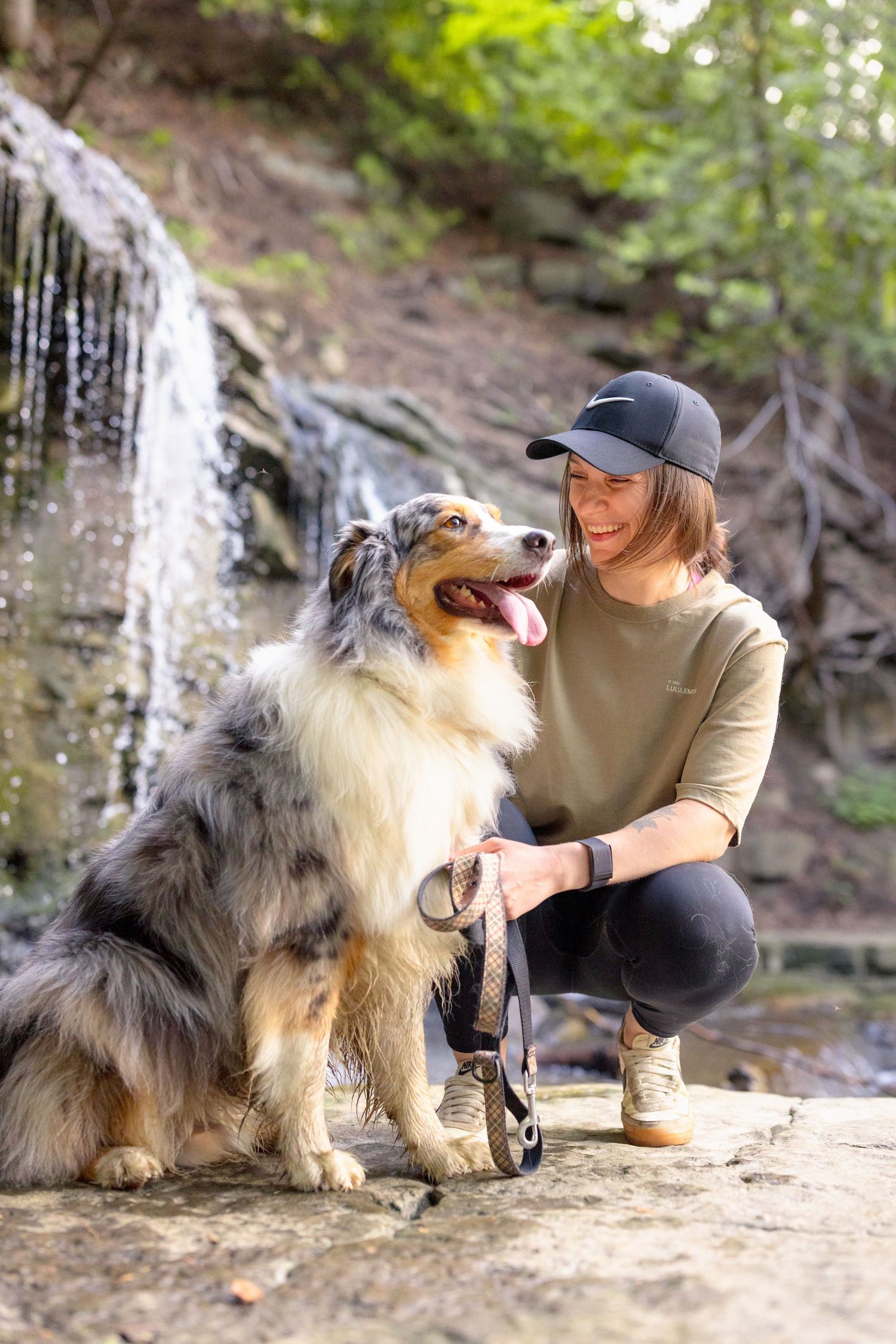 Australian Shepherd and companion pose together near a scenic waterfall. Ottawa Portrait Photographer