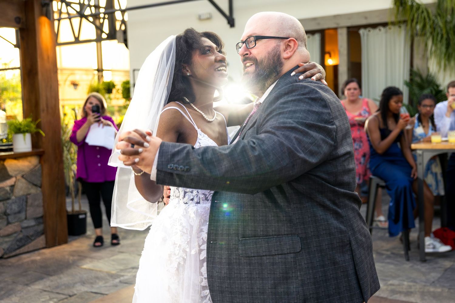 A couple shares their first dance as newlyweds during a wedding reception while guests look on and take photos. Tim Gowling Photography