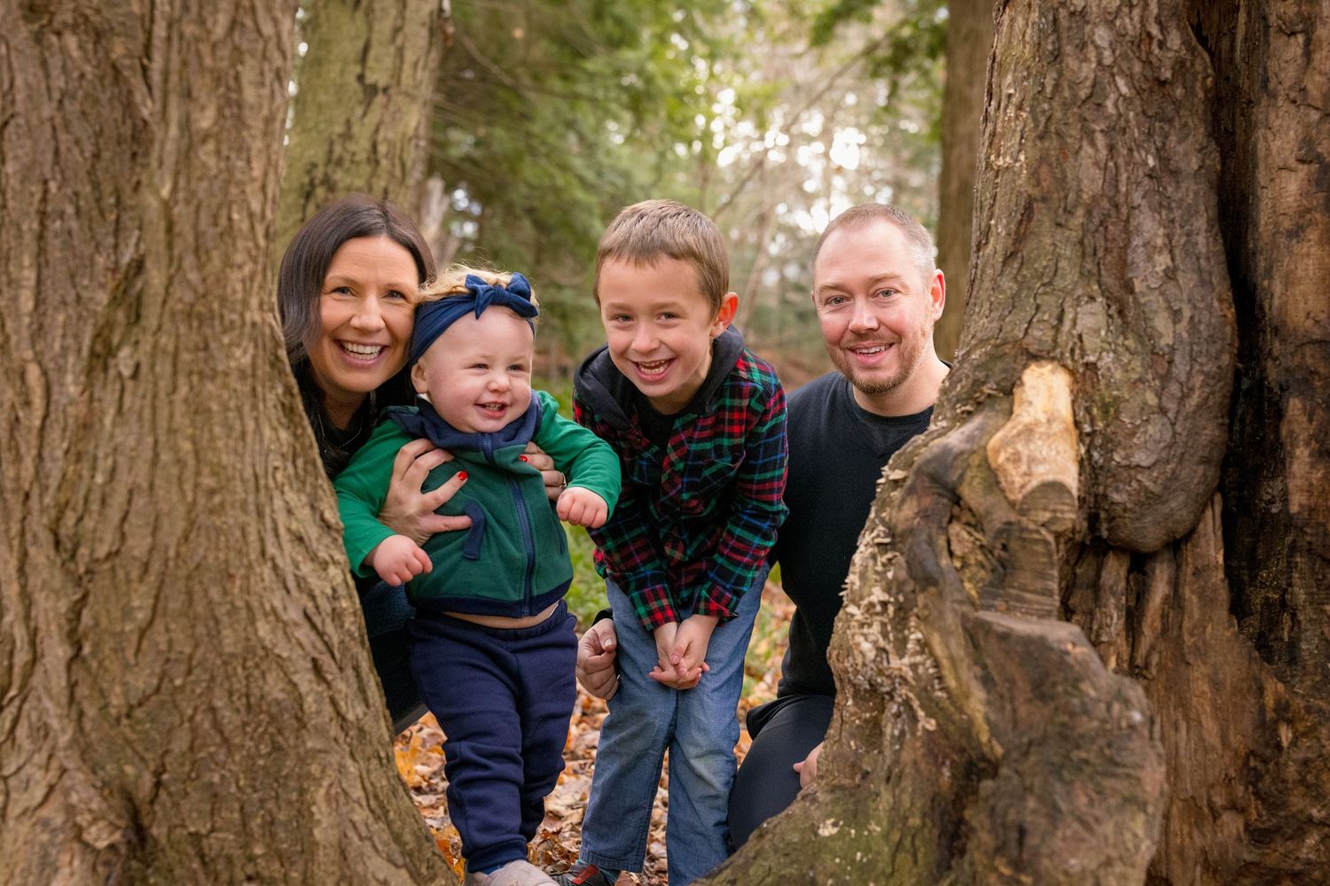 A family shares playful moments together on a wooden walkway in the woods. Ottawa Family Photographer
