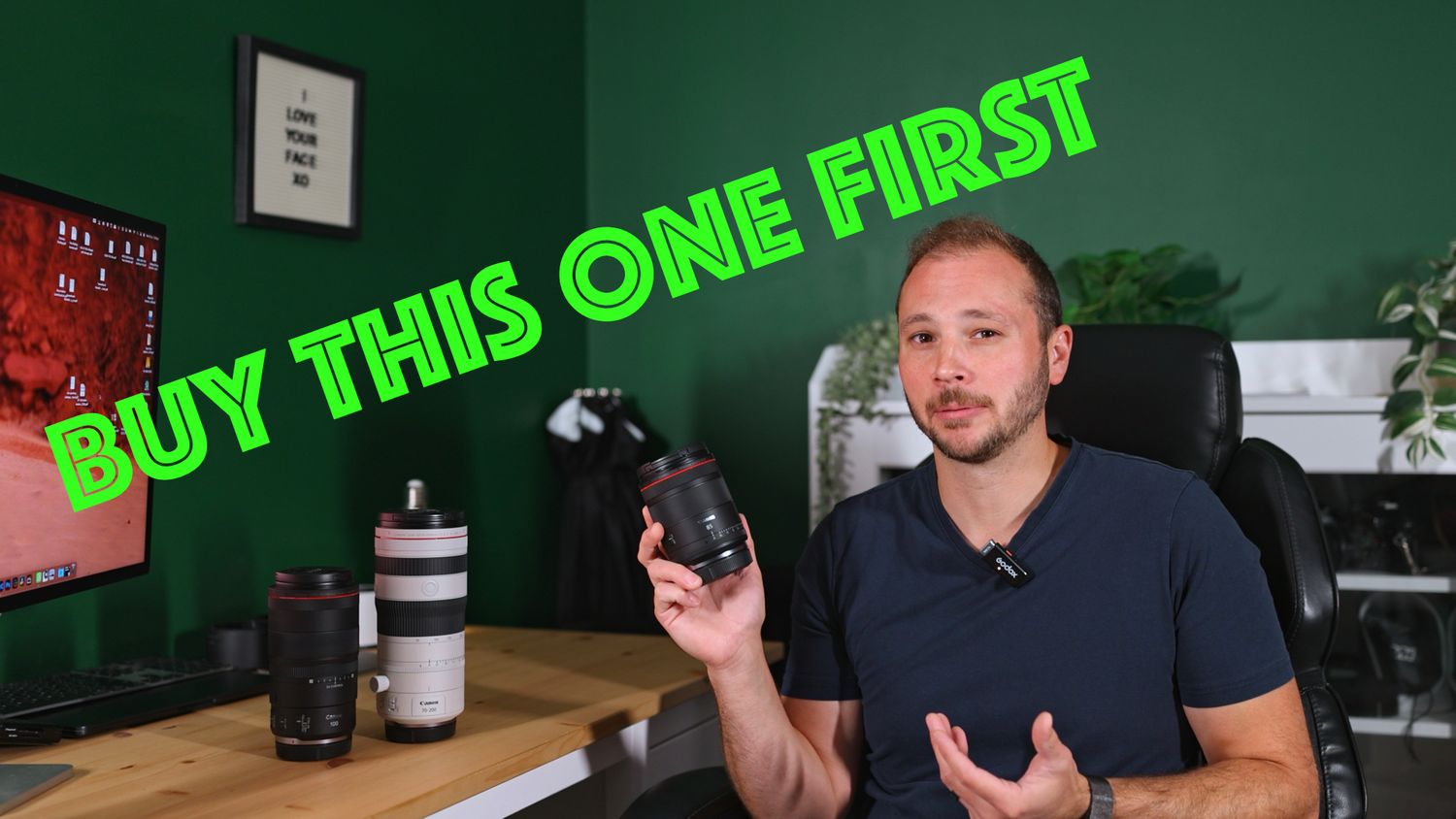 Man holding a camera lens with text Buy This One First on green background, offering photography gear buying advice.