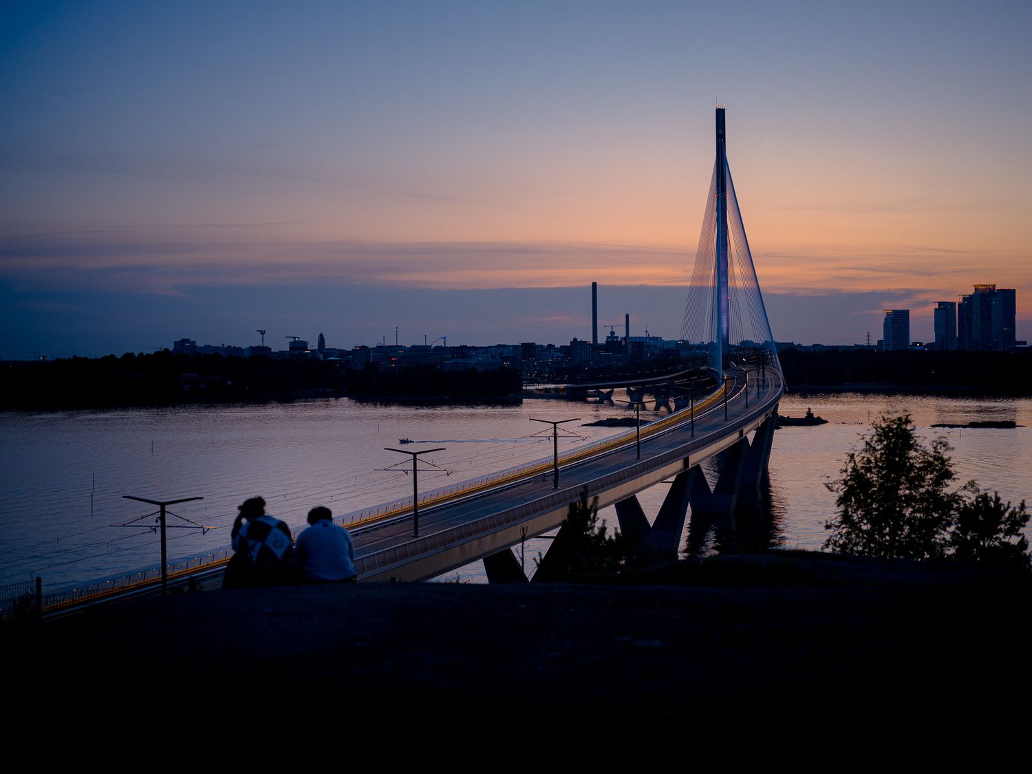 Kruunuvuoren silta jonka taustalla kaupungin siluetti, auringonlasku.
