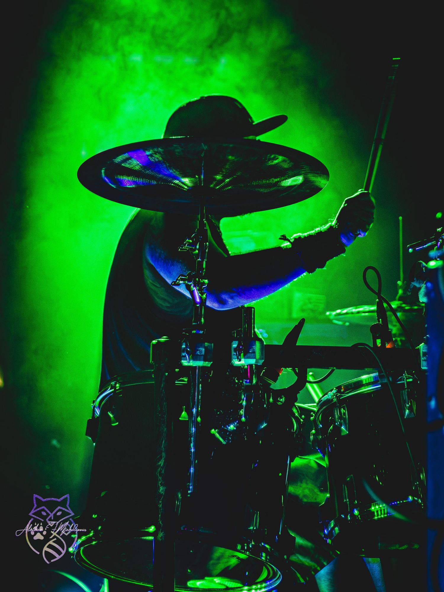 Silhouette of a drummer backlit by green.