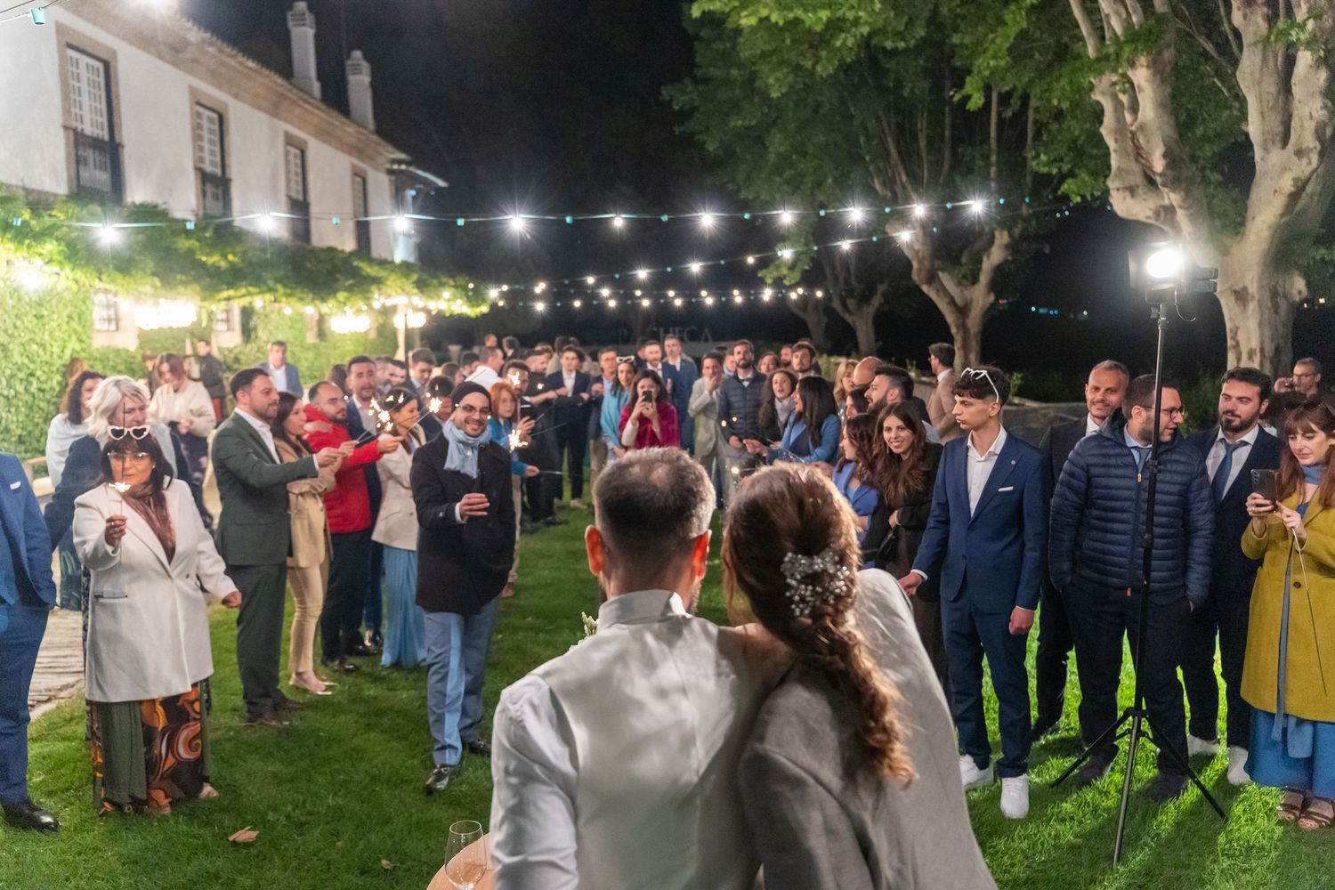 Convidados reunidos durante casamento na Quinta da Pacheca, Douro, ambiente ao ar livre com iluminação decorativa.