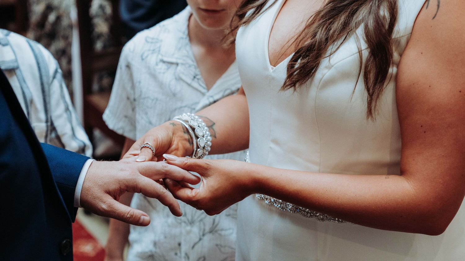 Bride placing wedding ring on grooms finger during intimate civil ceremony ring exchange.
