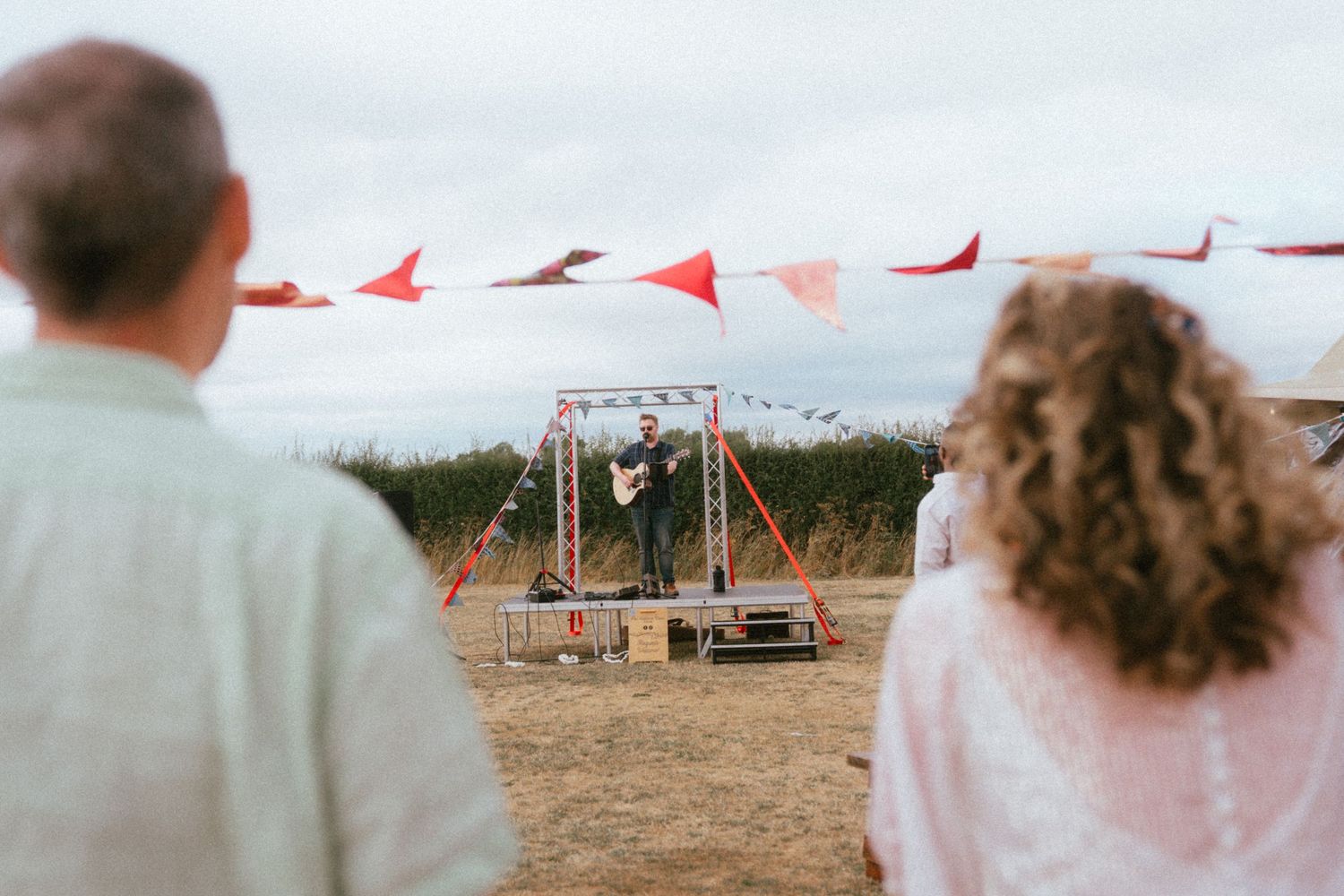Musician performing outdoors at a wedding ceremony with red and white bunting flags.