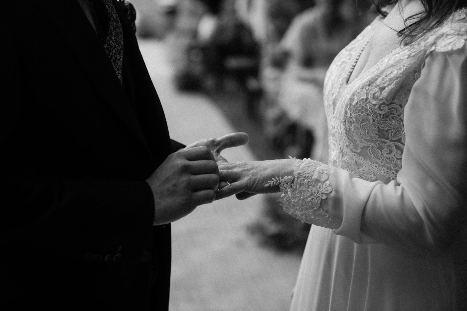Bride and groom exchanging rings during outdoor wedding ceremony in black and white.