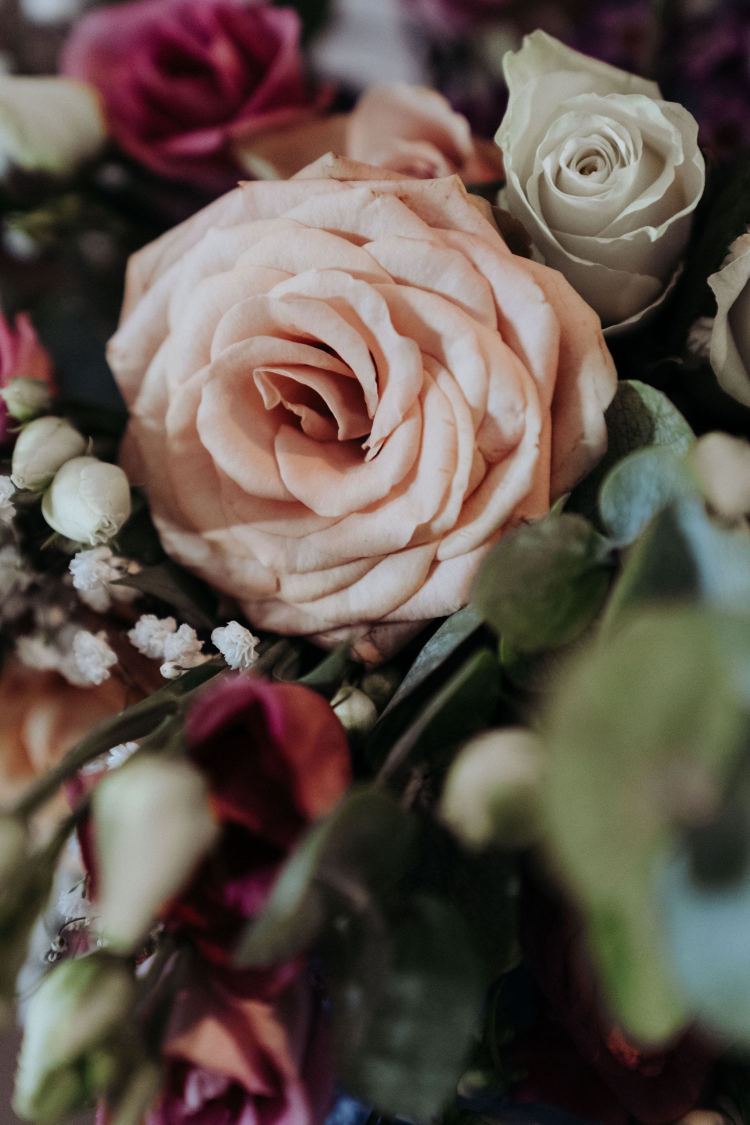 Close-up of elegant blush pink and cream roses in a romantic wedding bouquet arrangement.