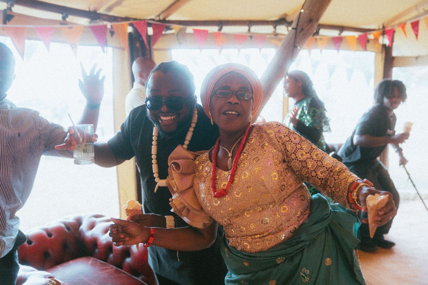 Two people dancing joyfully at a colorful wedding reception celebration indoors.