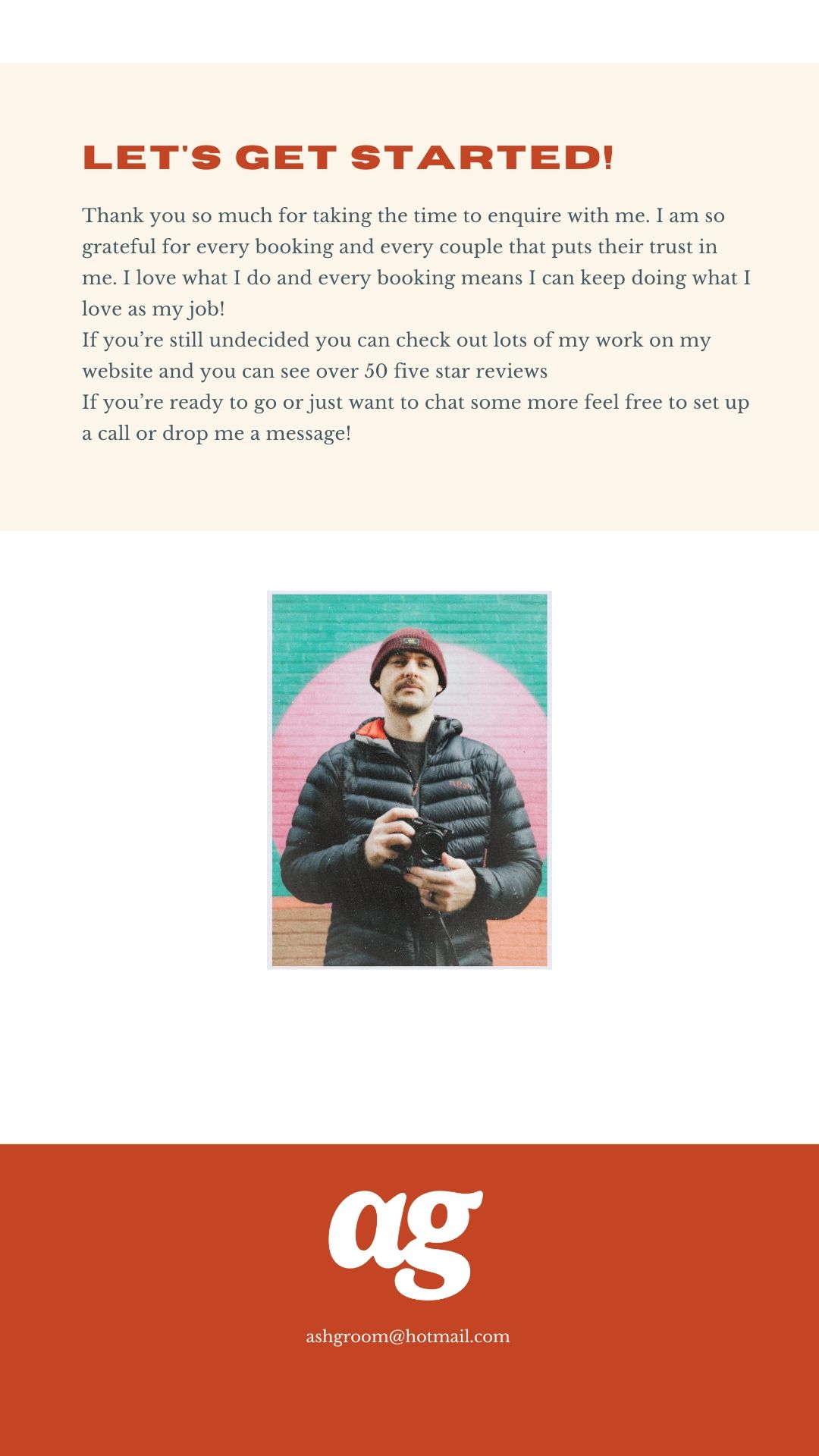A male photographer holding a camera stands in front of a colorful mural, wearing a black puffer jacket and red beanie.