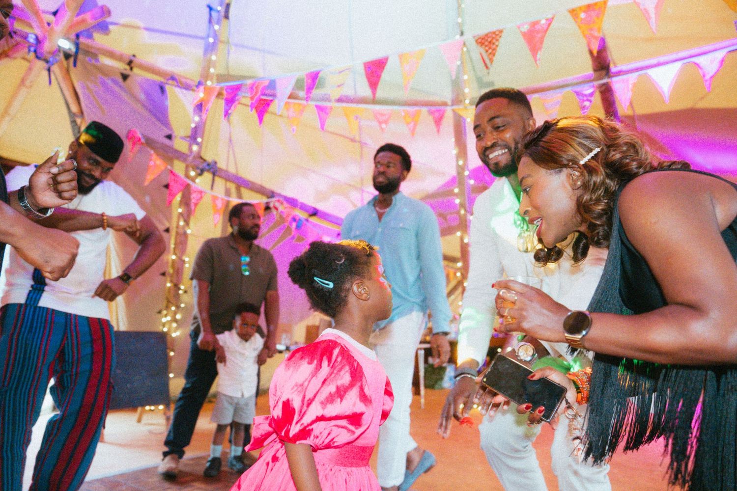 Guests dancing and celebrating at a vibrant colorful wedding reception under a tent.