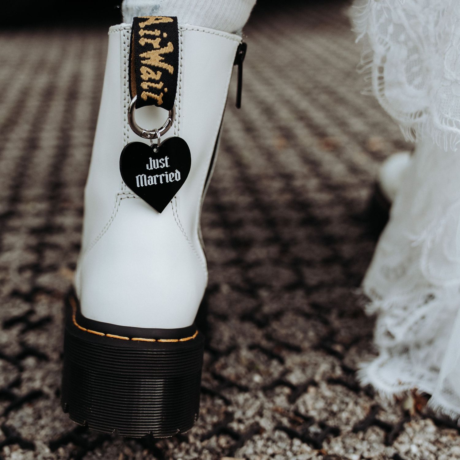 White Dr Martens boots with black heart Just Married charm worn by bride on wedding day.